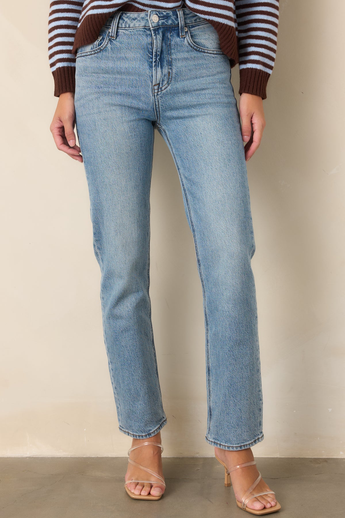 High-rise denim jeans showcasing the closely fitted waist and straight-leg silhouette.
