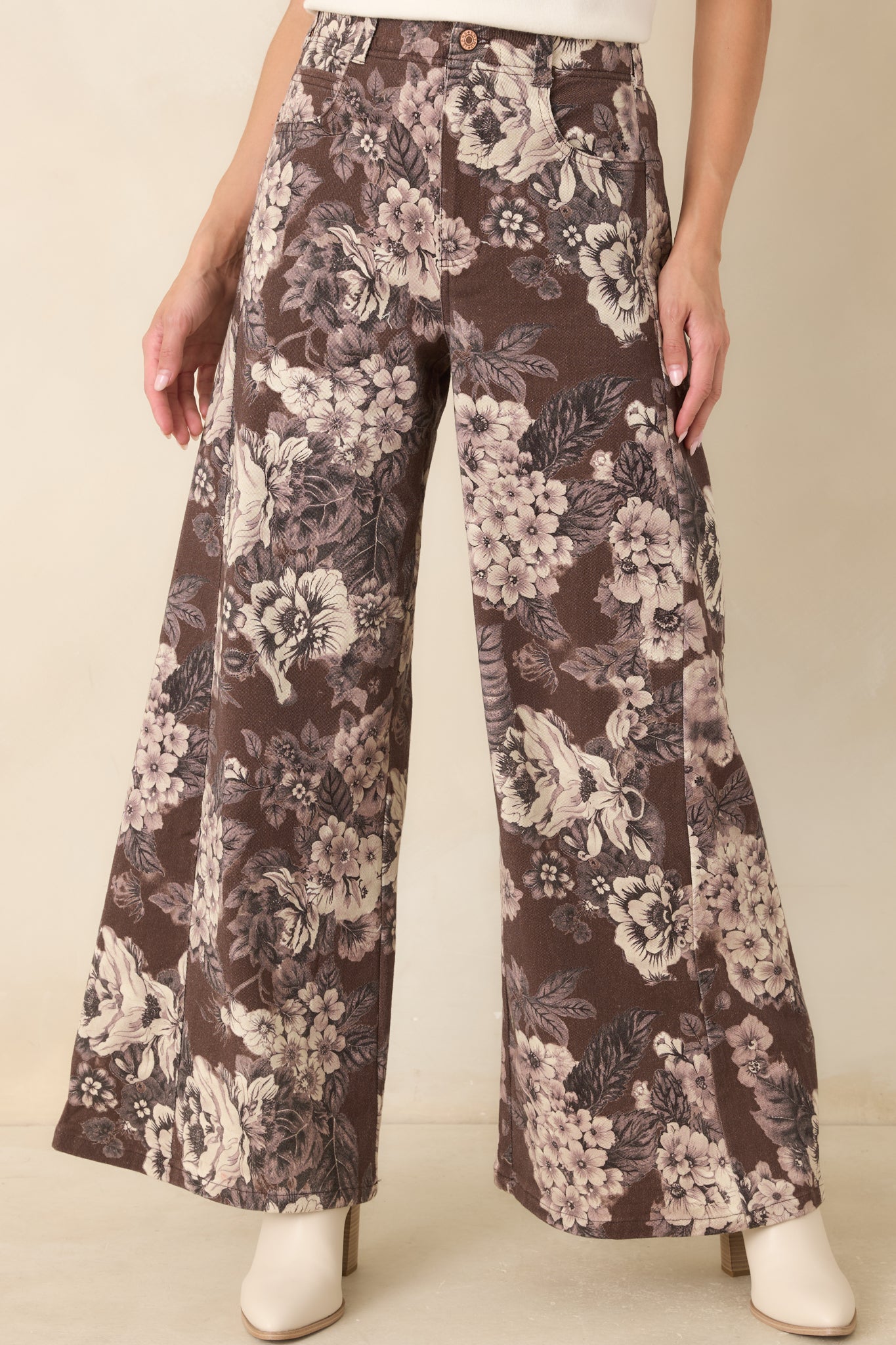 Close view of the pants highlighting the high-rise waistband, belt loops, button-and-zip closure, and ivory floral print.