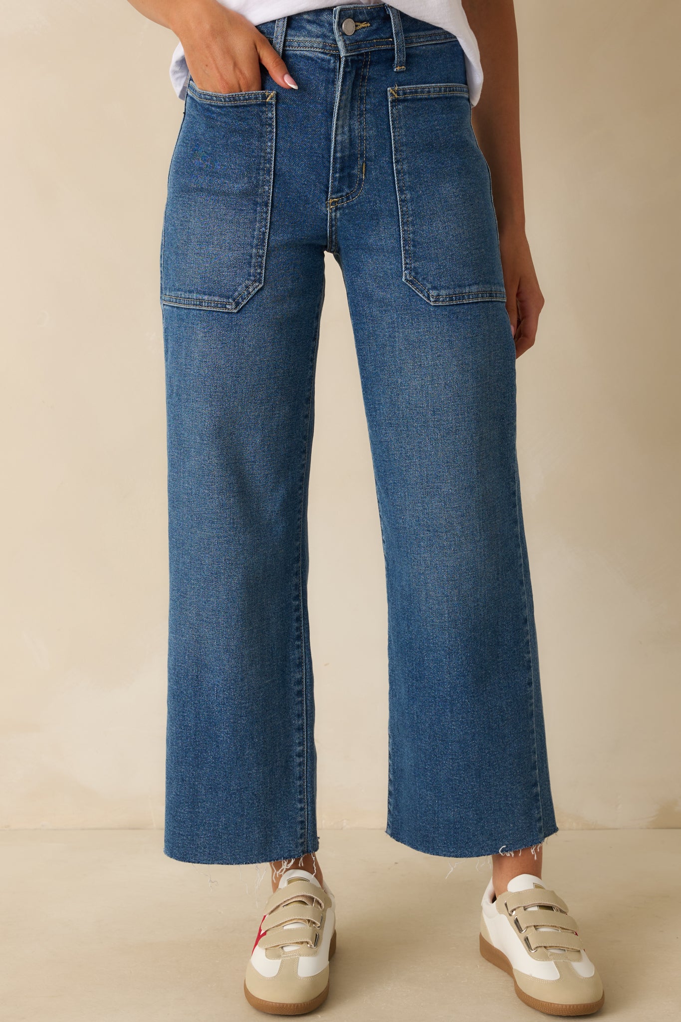 Medium wash utility jeans with high-rise waist, wide-leg silhouette, and raw-cut hem.