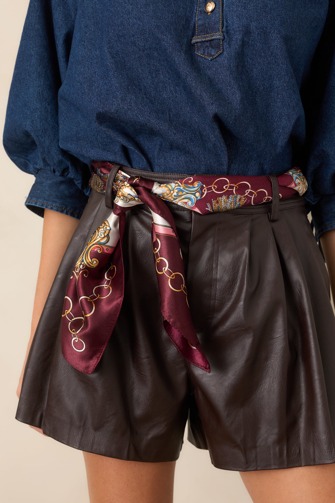 Close-up highlights the high-rise waistband, precise front pleats, and smooth polyester-lined construction.