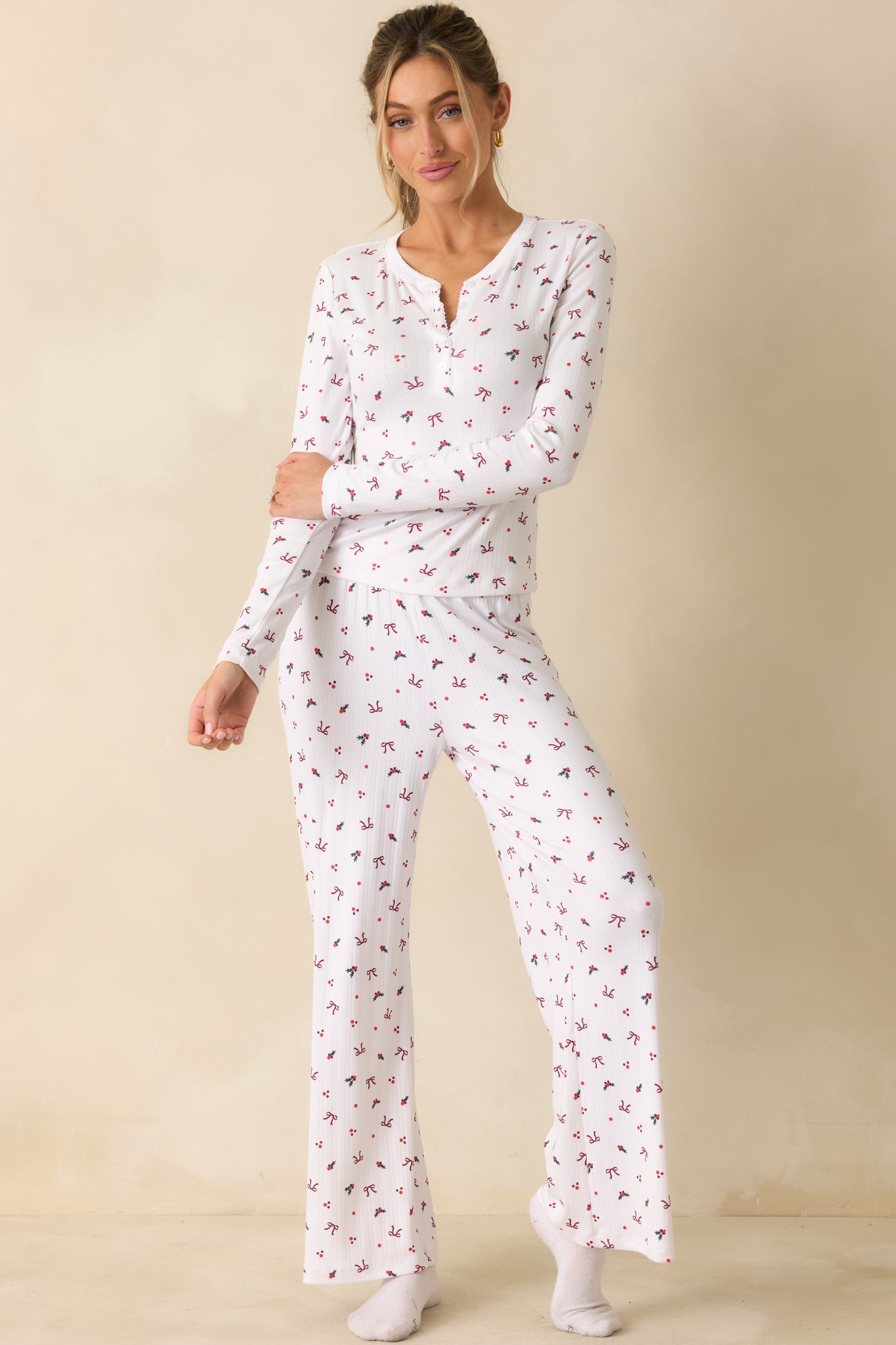 High-rise white pants with a wide-leg cut, soft-wash finish, and seasonal holly-and-bow print throughout.