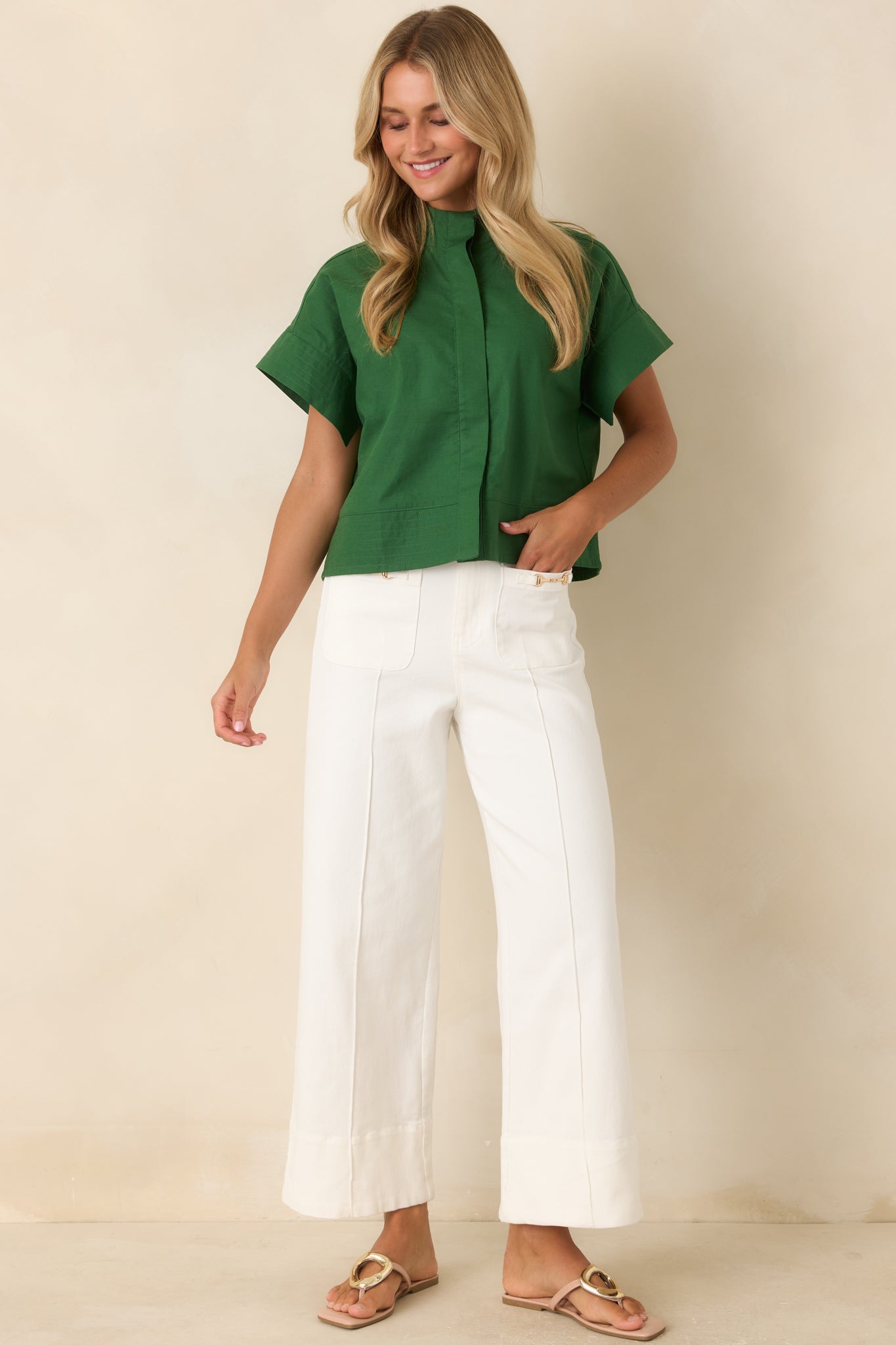 High-rise wide leg pants featuring crisp front pleats, gold-tone hardware on patch pockets, and a polished cotton blend finish.
