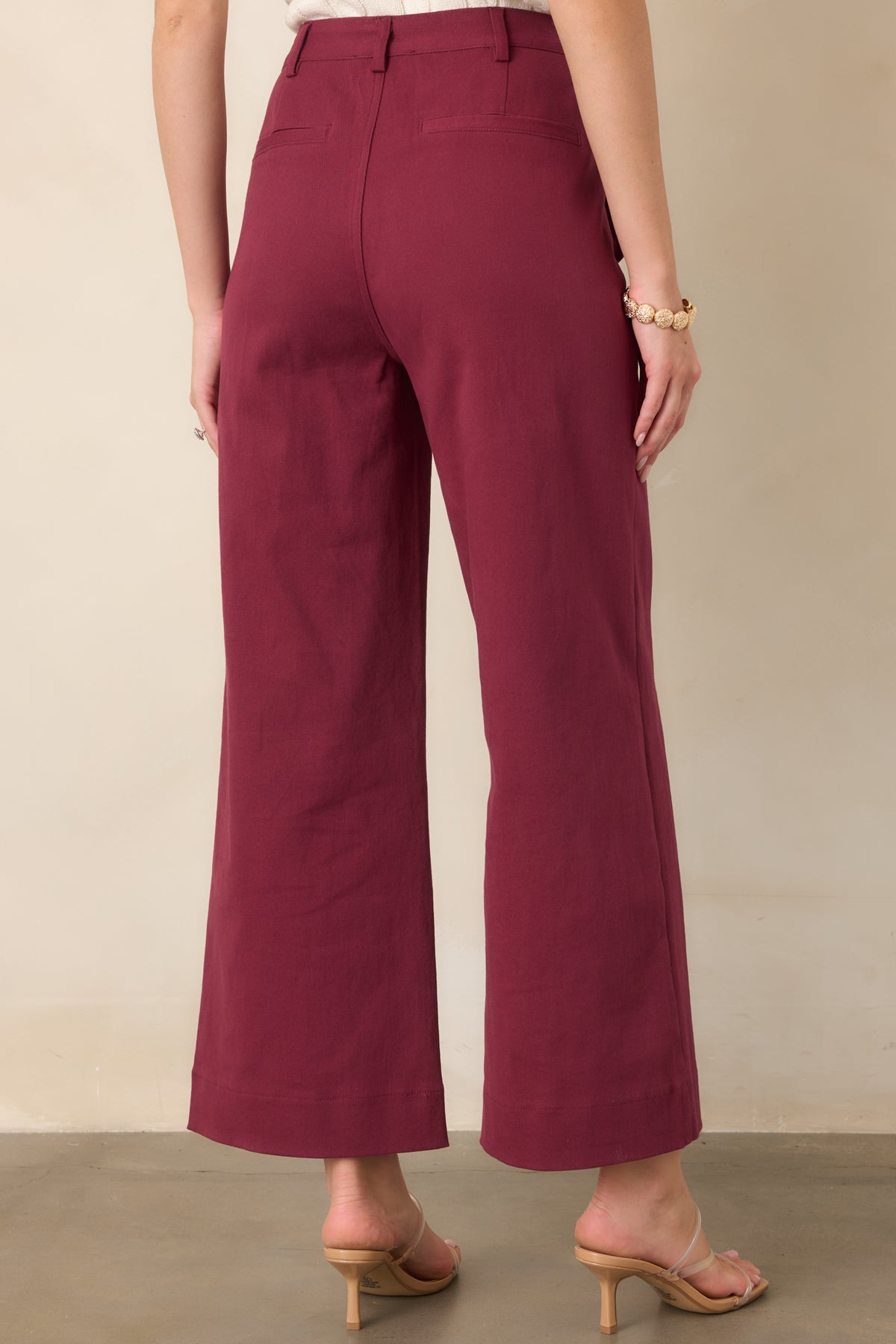 Rear view of the high-rise wide-leg pants showing the structured waistband, belt loops, functional back welt pockets, and flowing wide-leg silhouette.