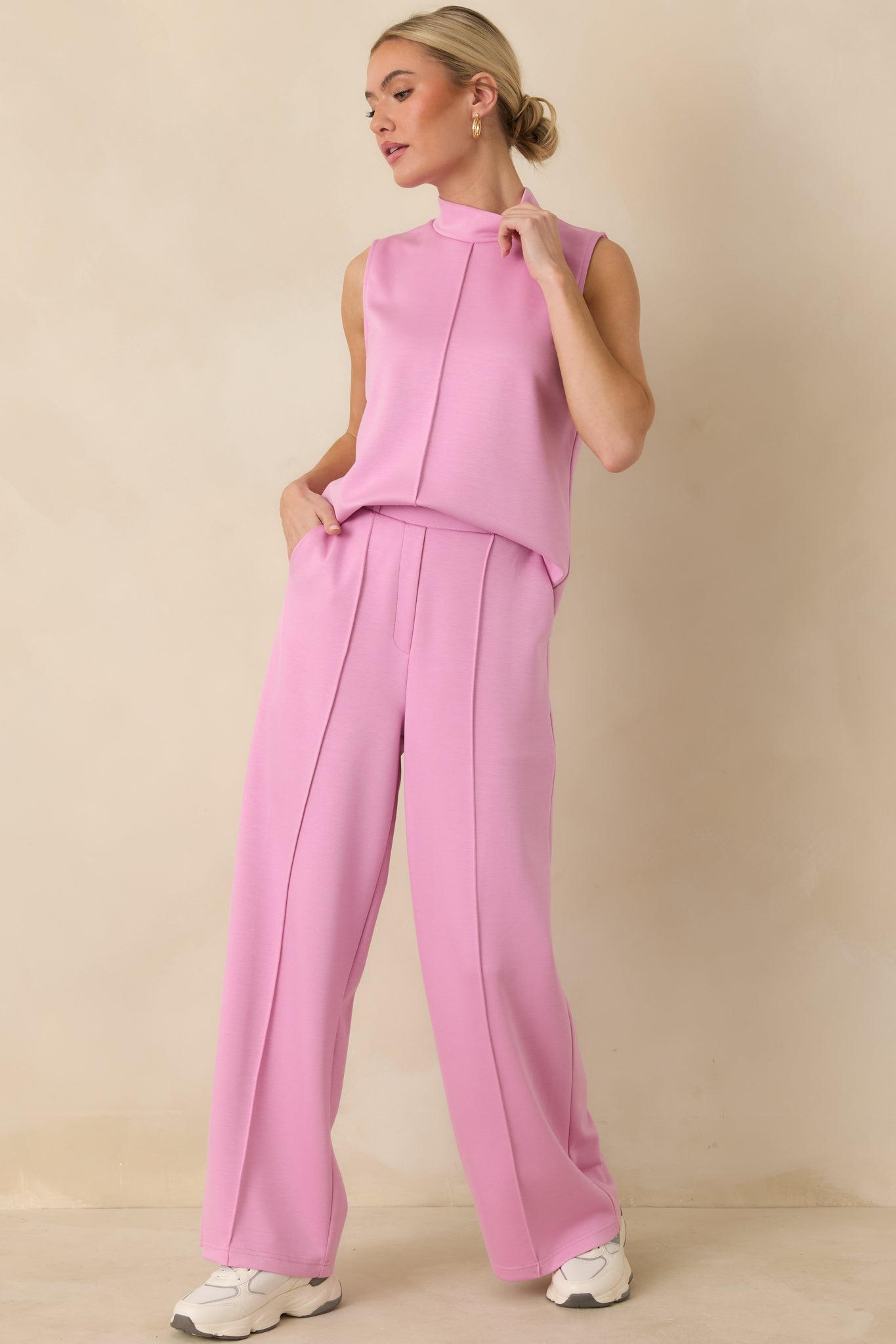 High-waisted pink pants featuring soft knit fabrication, front pleats, and an effortless yet refined silhouette.