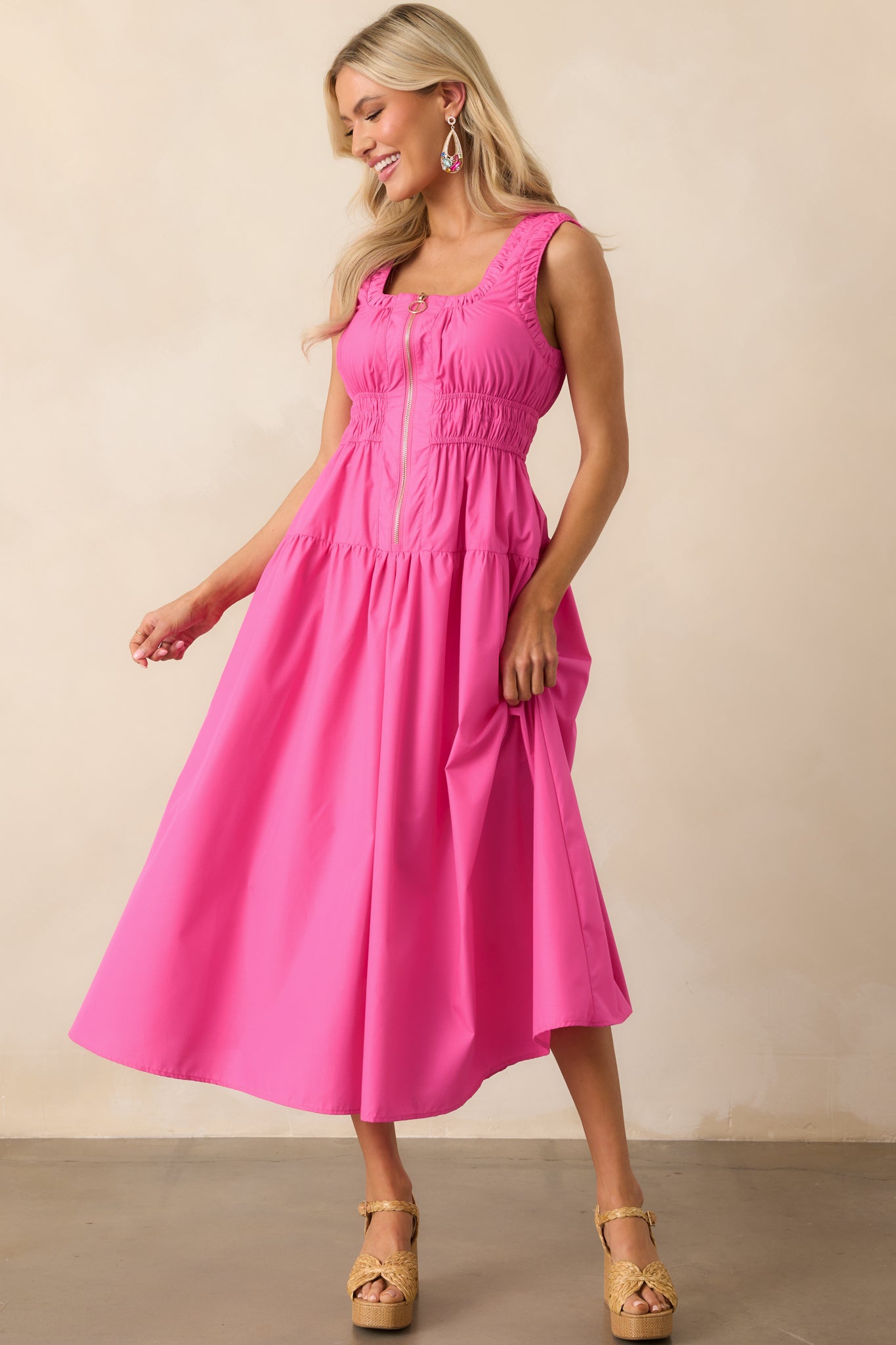 Front-facing image of a hot pink midi dress with visible ruched waistline and functional pockets on each side.
