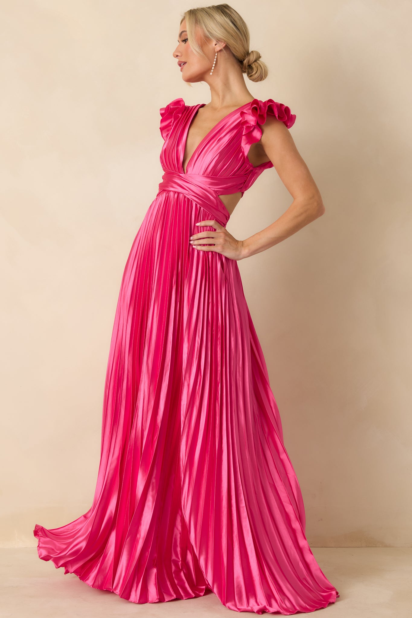 Front view of hot pink pleated maxi dress with deep V-neckline, ruffled cap sleeves, and fixed wrap-style bodice.