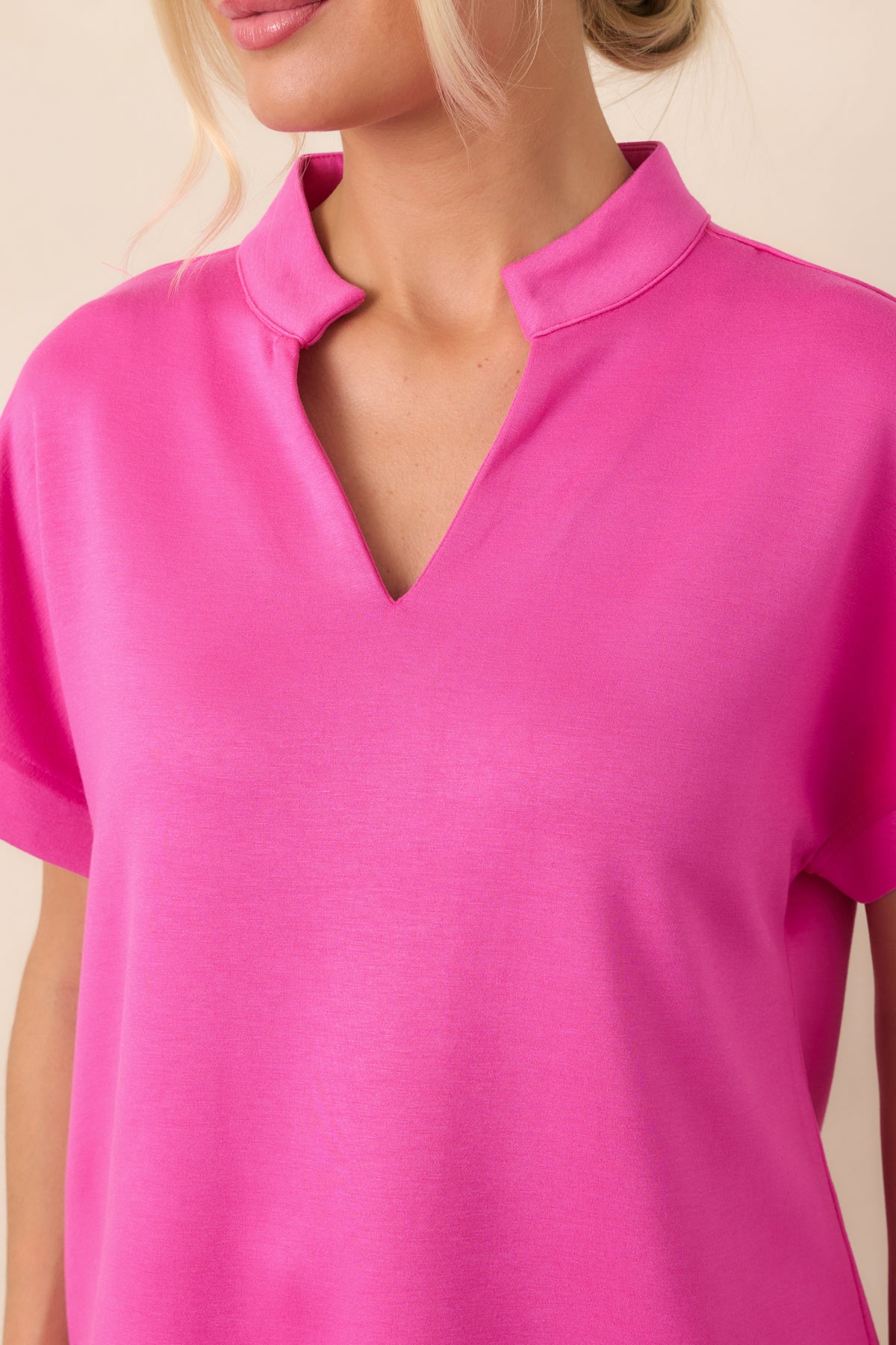 Close-up of the hot pink split neckline and standing collar, highlighting the crisp structured finish and vibrant color.