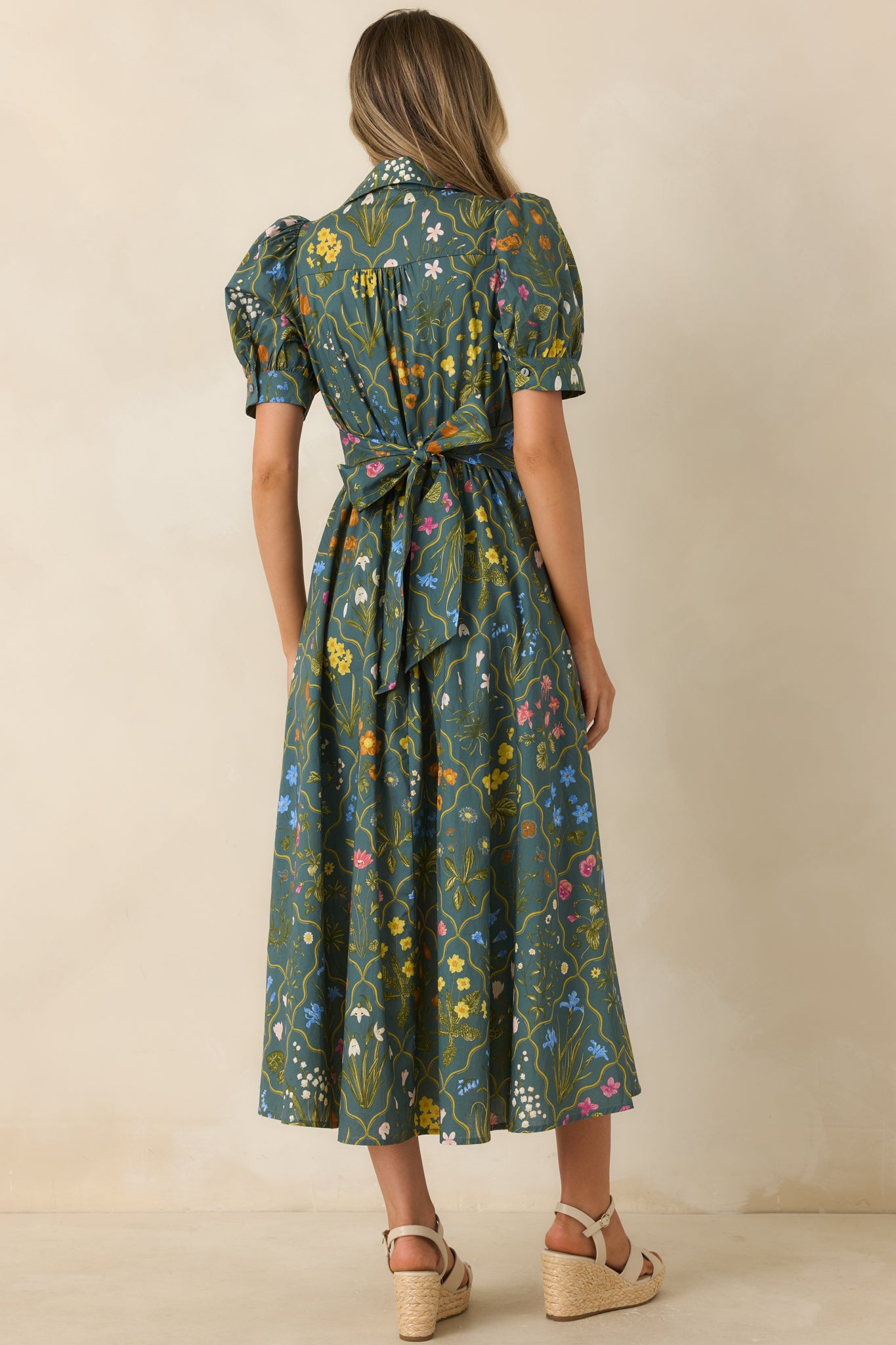 Back view of the hunter green floral midi dress featuring an elastic waistband, full skirt, and softly structured puff sleeves.