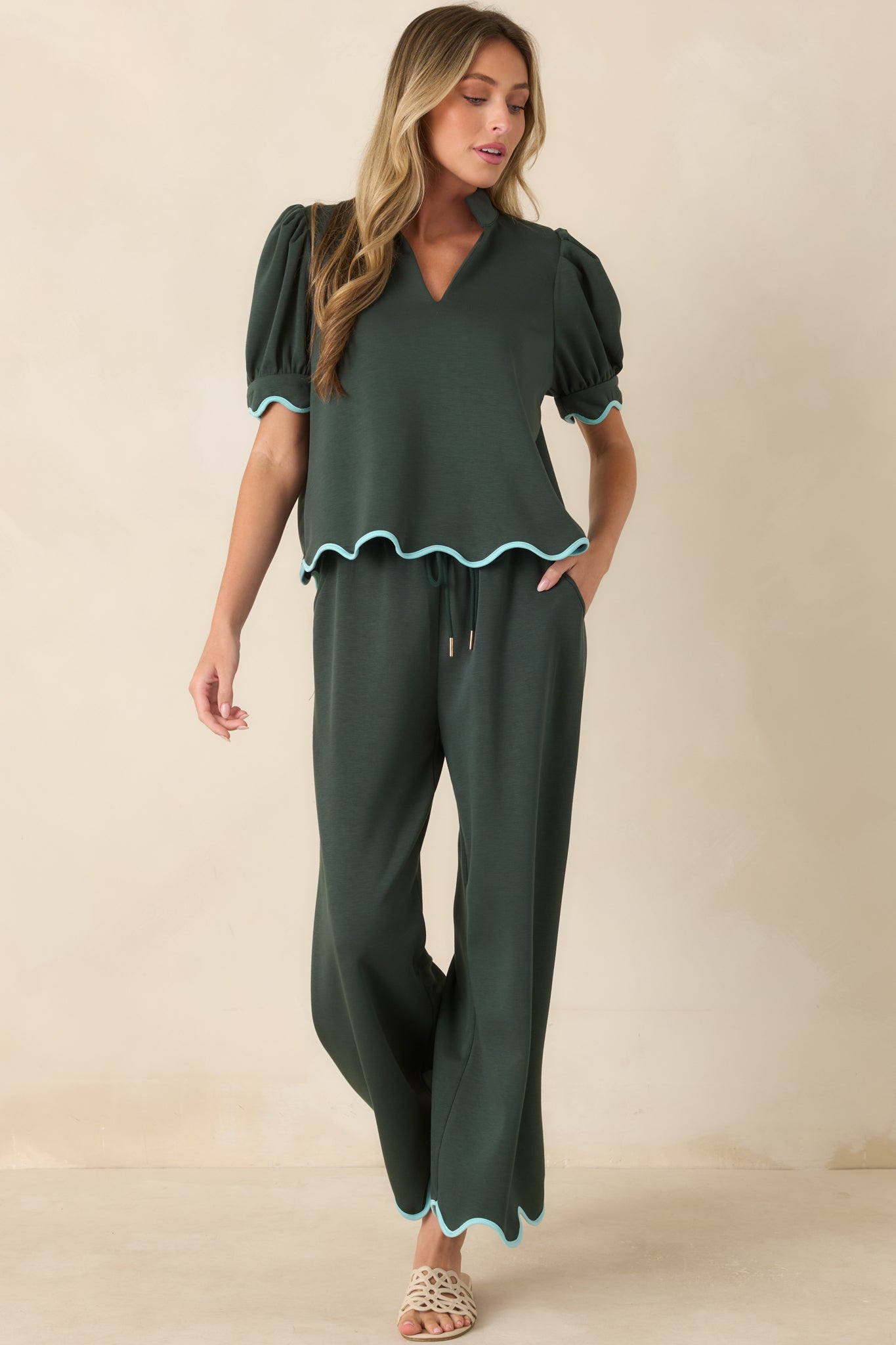 Hunter green knit top featuring a split neckline, stand collar, puff sleeves, and light blue scalloped trim.