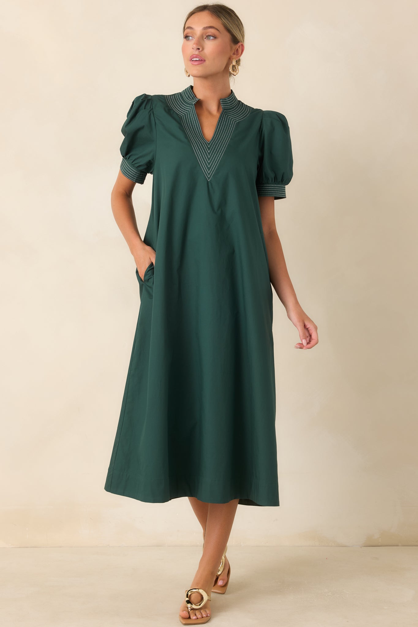 Hunter green midi dress featuring a structured split neckline, contrast stitching, and short puff sleeves.
