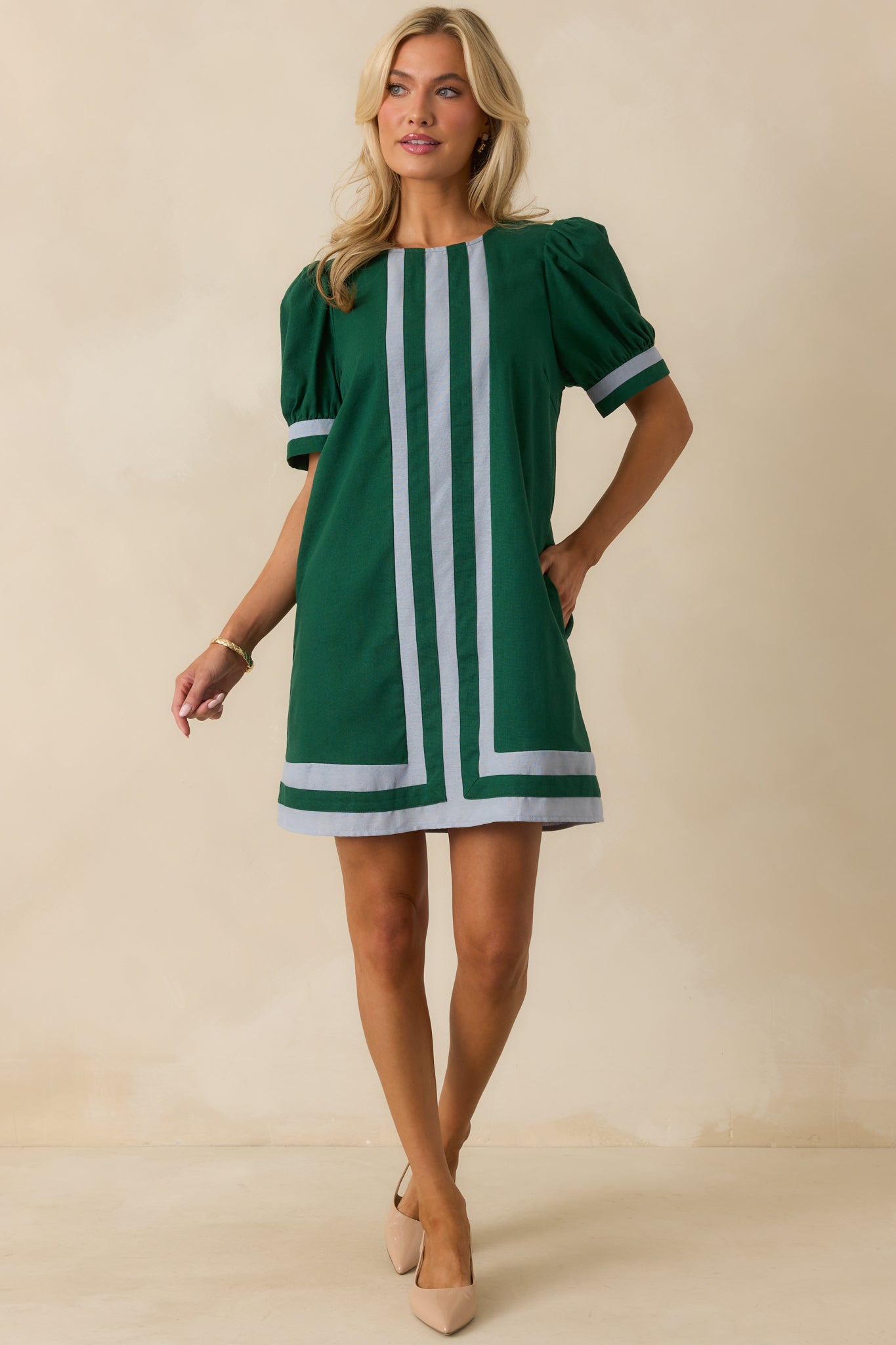 Hunter green mini dress with short puff sleeves, round neckline, functional pockets, and light blue contrast stripe running down the center.