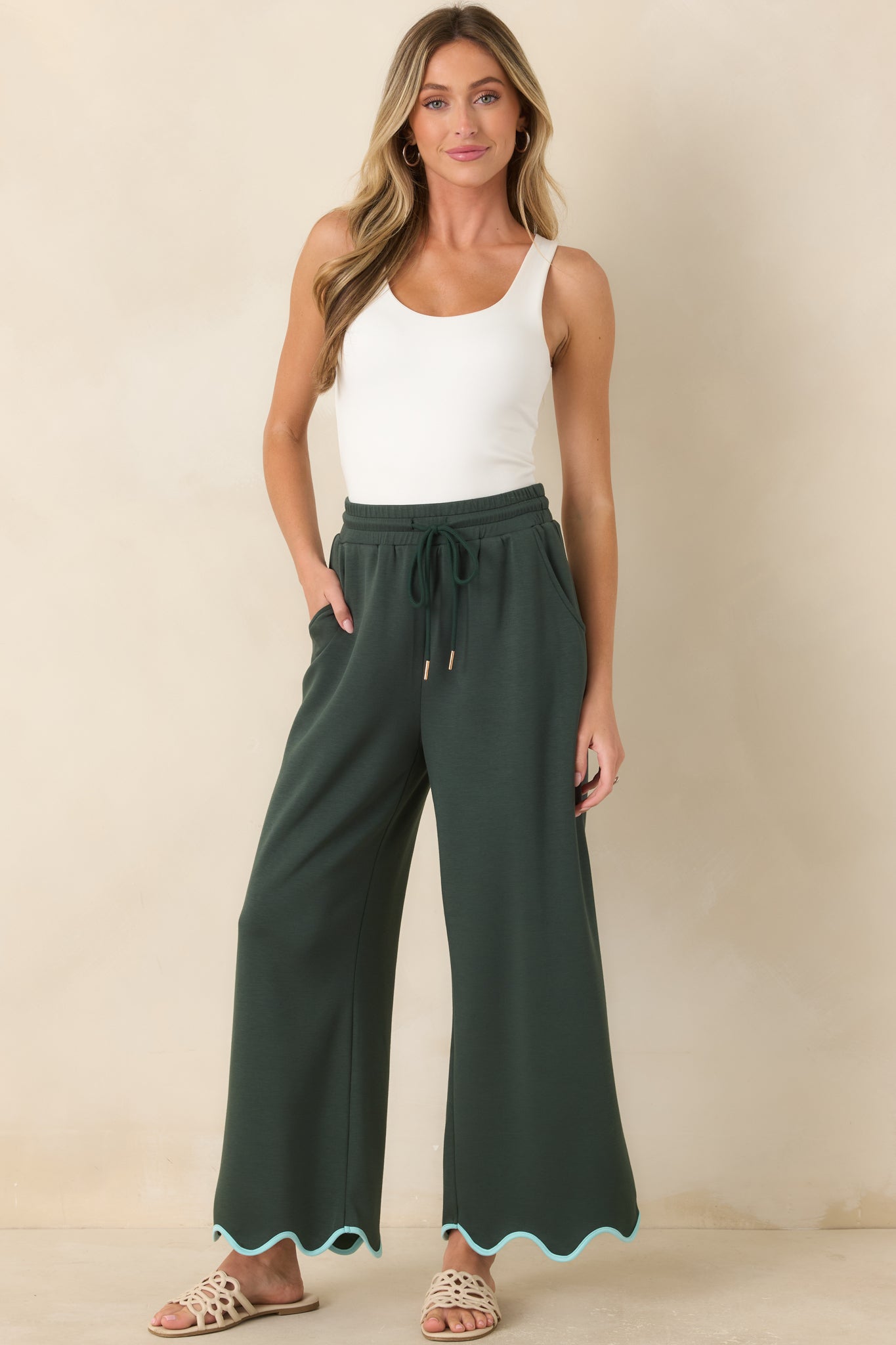 Hunter green wide leg pants featuring soft knit fabric, a relaxed fit, and refined scalloped hem detailing.