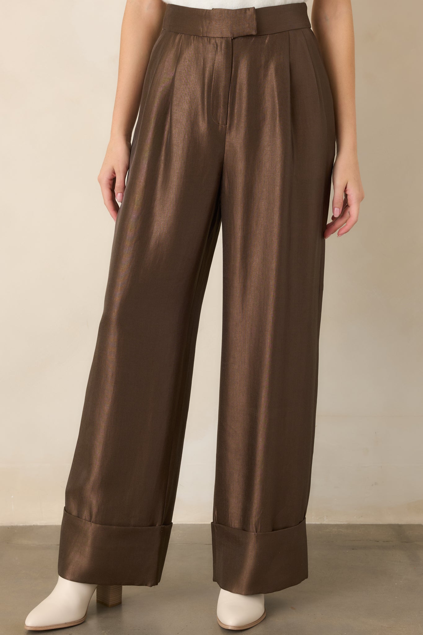 Iced brown pants highlighting the high-rise waistband, crisp front pleats, and smooth, fluid fabric.