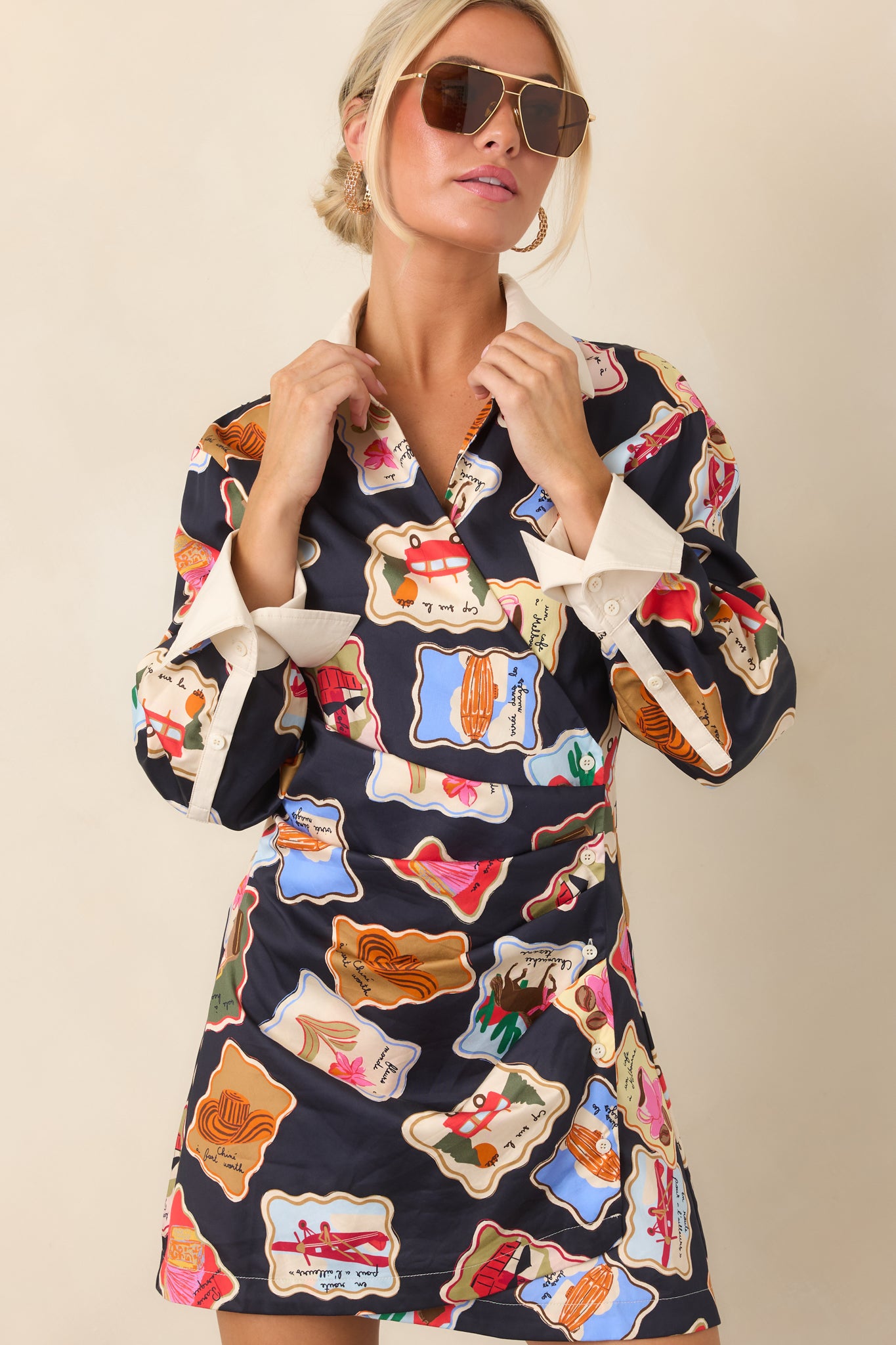 Close view of the mini dress highlighting its colorful illustrated stamp motifs, ivory collar, and gathered crossover front.