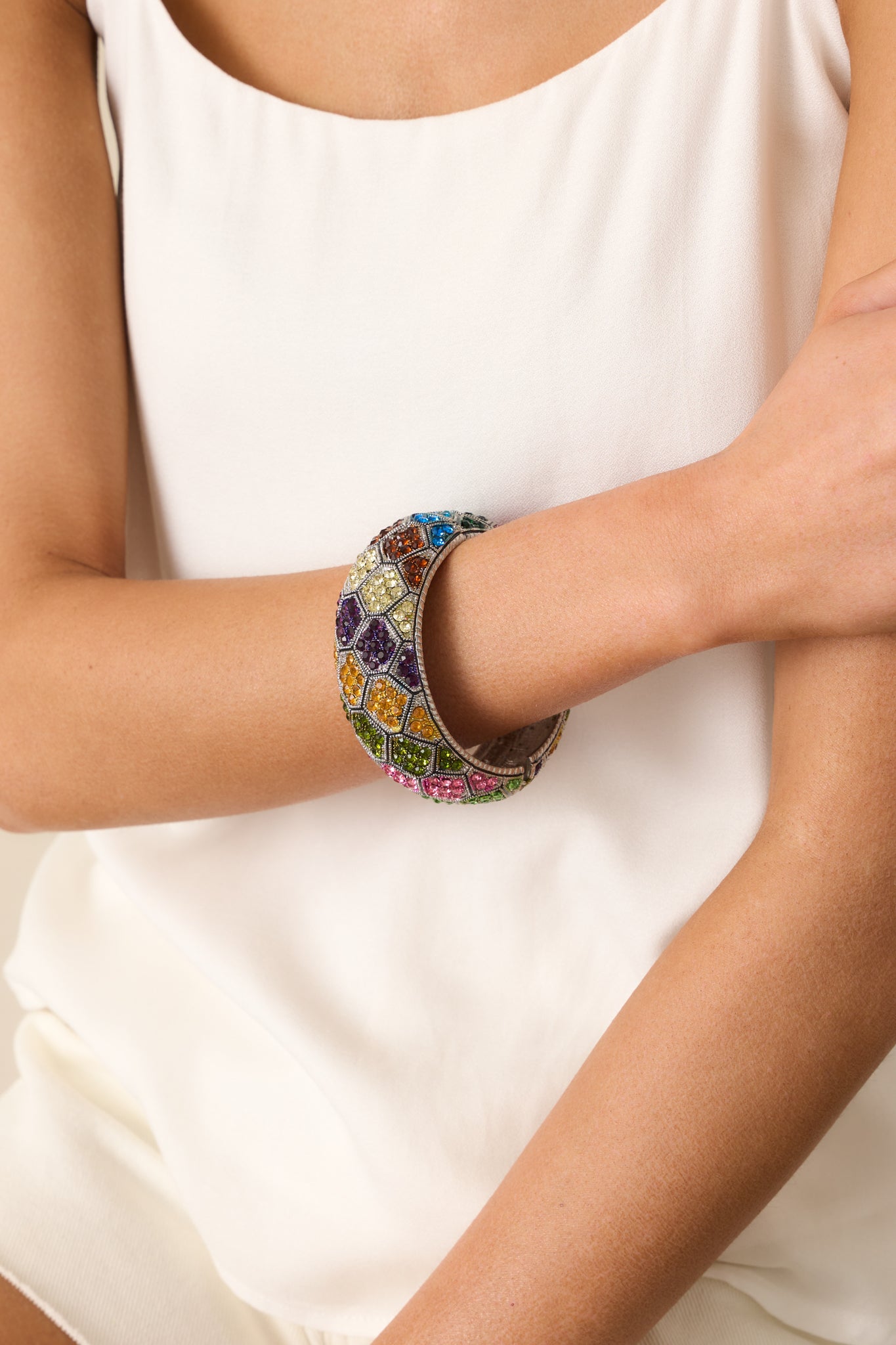 Tightly framed image highlighting the hinge area and part of the multicolored rhinestone design on the silver cuff.