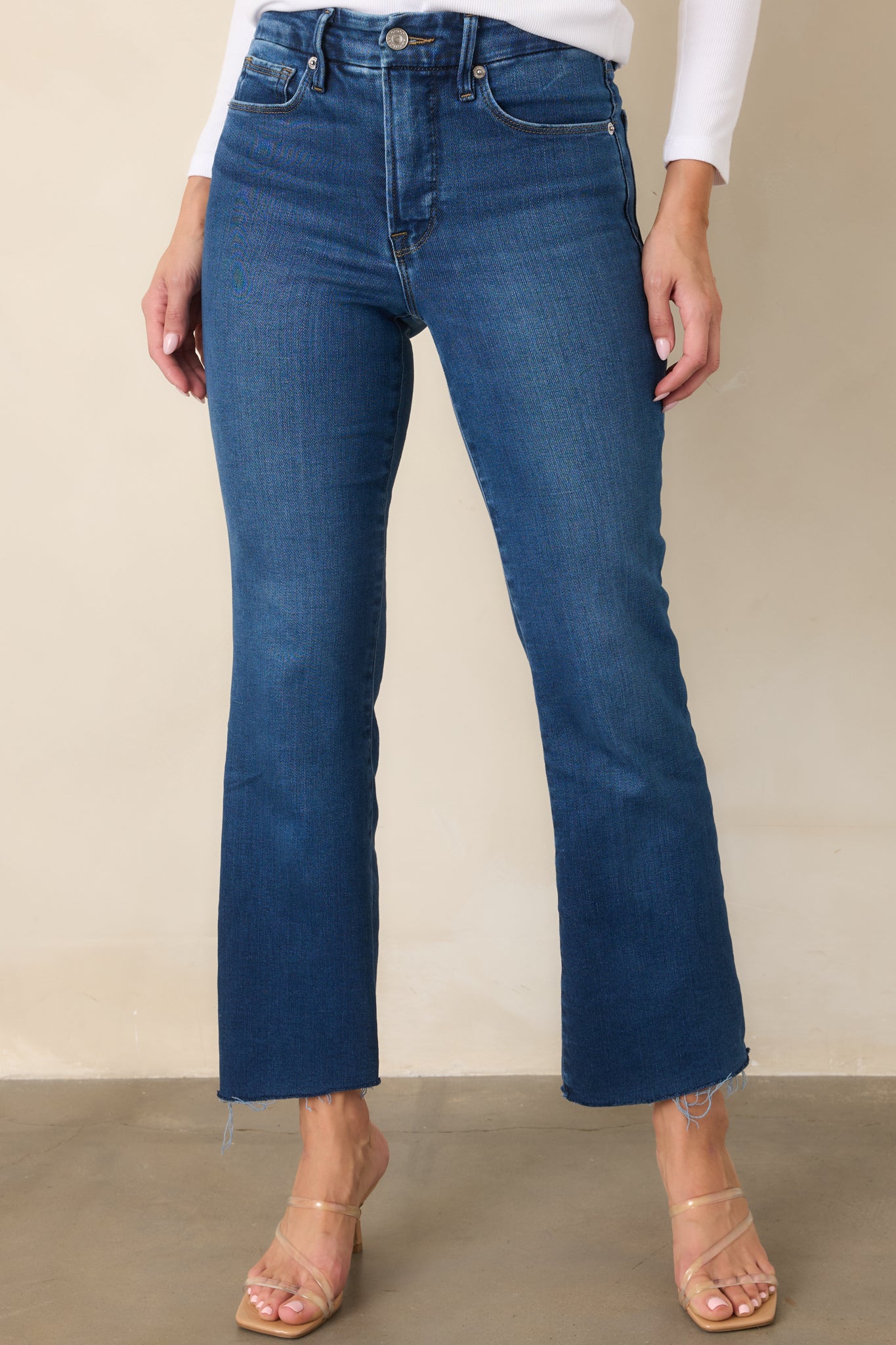 Front view emphasizing the medium indigo wash, cropped length, and softly flared raw hems.