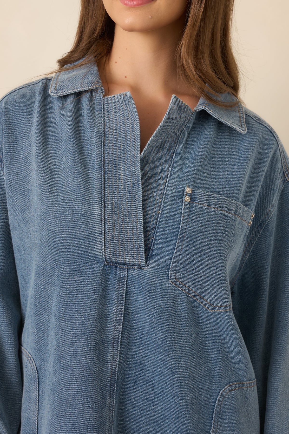 Close-up of the structured indigo denim showcasing the classic collar, partial button placket, and visible fabric texture.