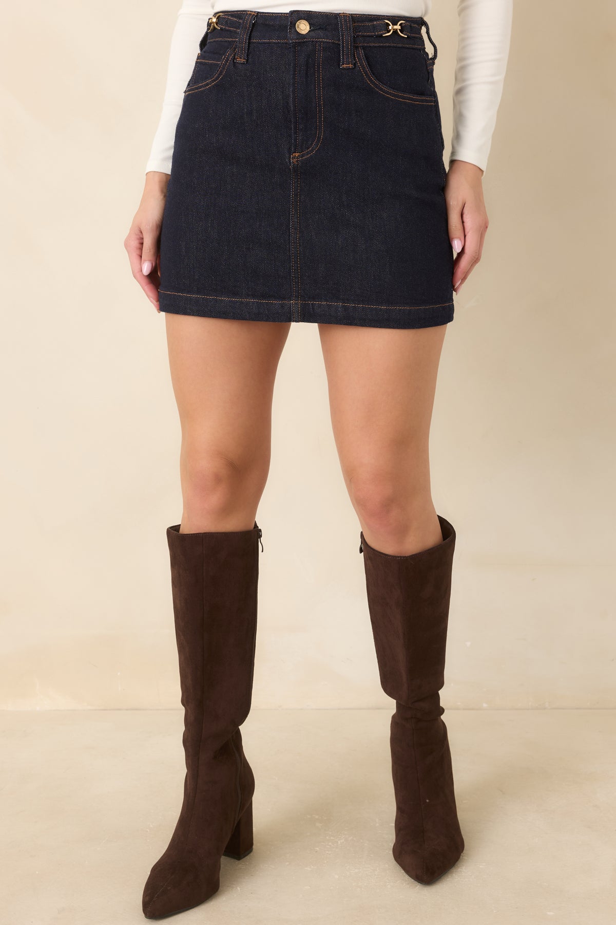 Indigo denim mini skirt showcasing its waistband, belt loops, and gold-tone button closure.