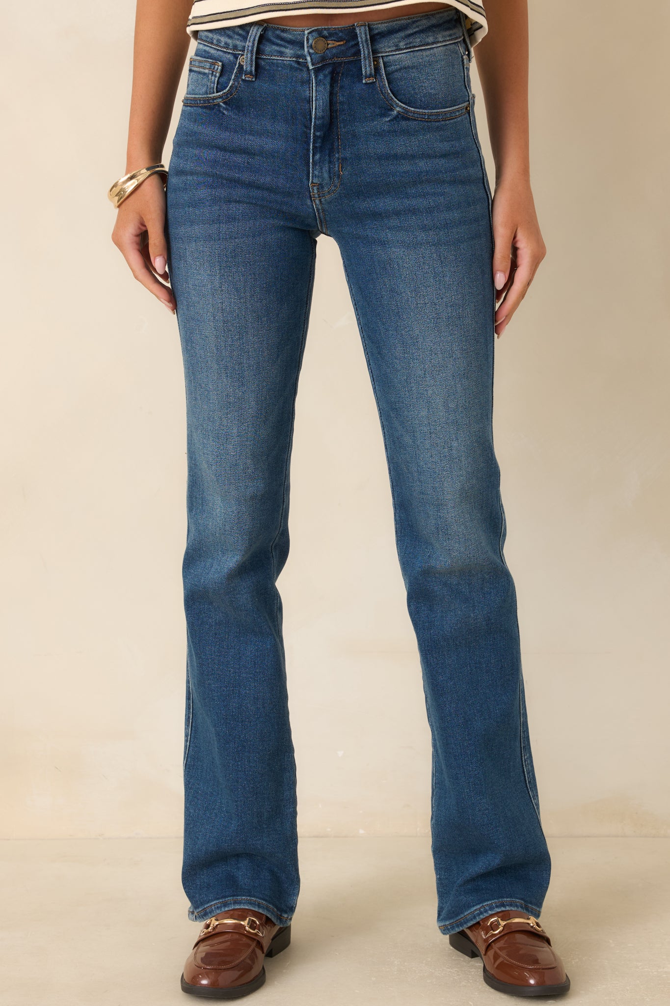 Front view of dark indigo jeans highlighting the high rise, zip fly with button closure, belt loops, and classic five-pocket styling.