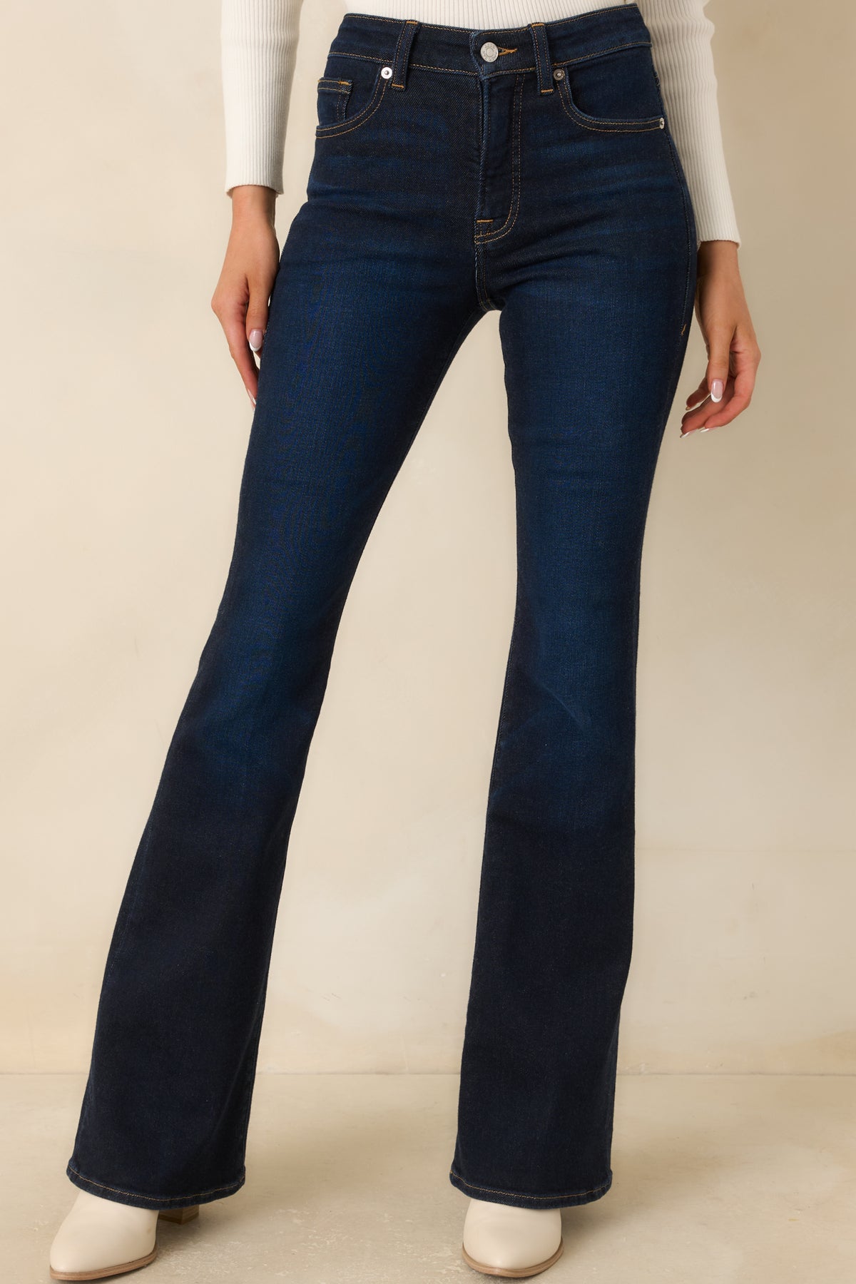 Deep indigo denim waistband with belt loops, a classic button closure, and contrast stitching along the pockets.