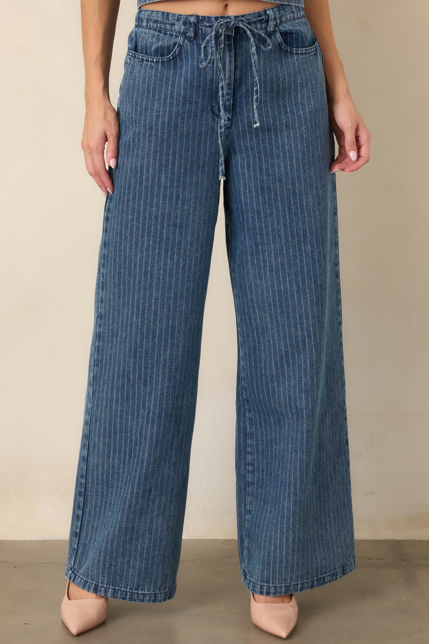 Front detail of the indigo striped pants highlighting the elastic waistband, adjustable drawstring tie, and vertical stripe pattern.