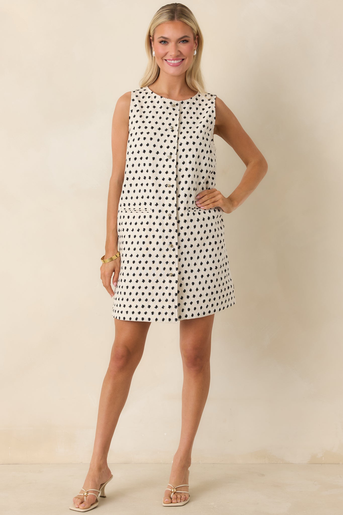 Ivory and black patterned mini dress with refined structure and sleeveless cut.