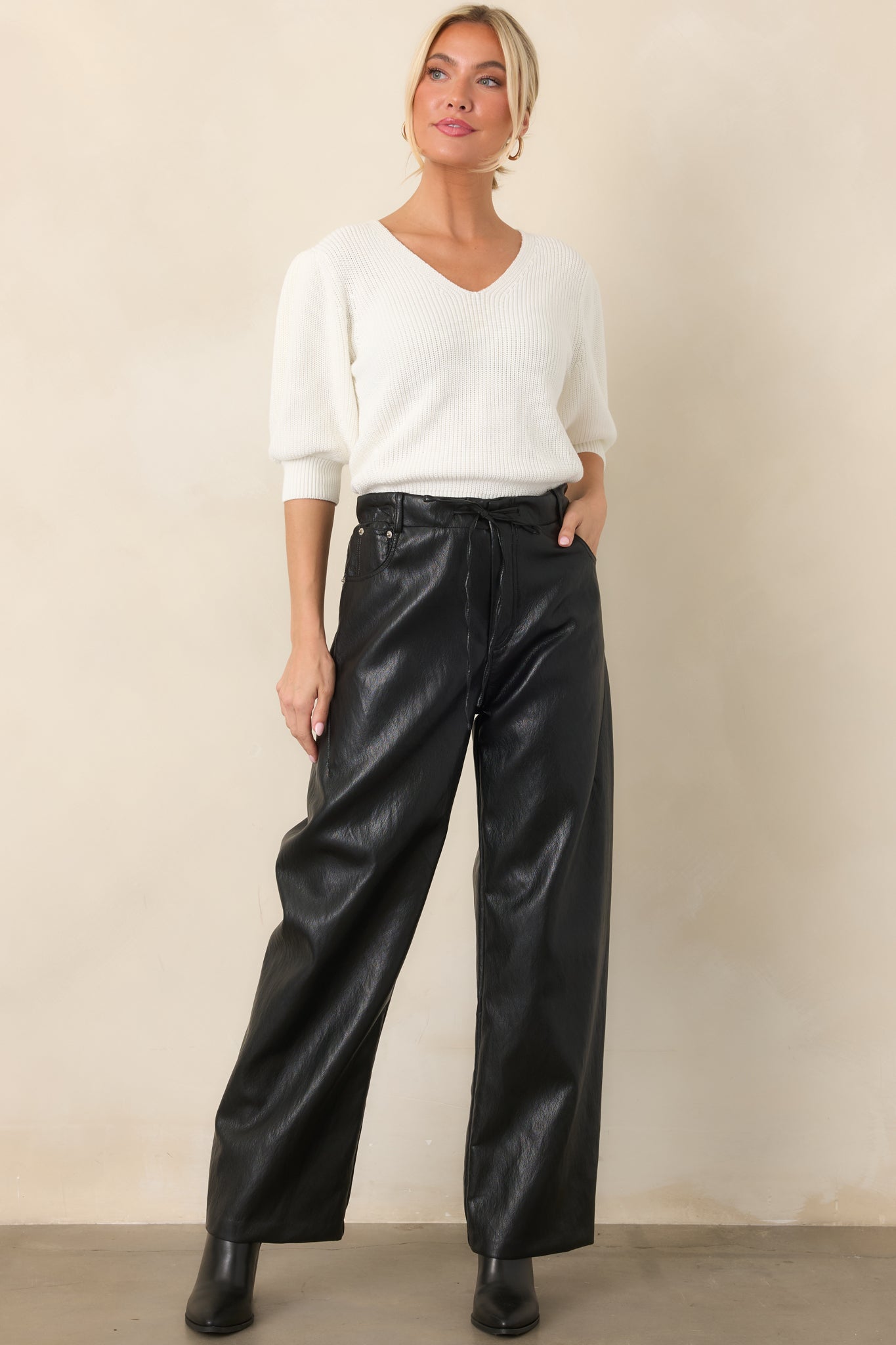 Ivory blouse with a softly structured shape, gathered shoulders, puffed elbow-length sleeves, and ribbed hem.