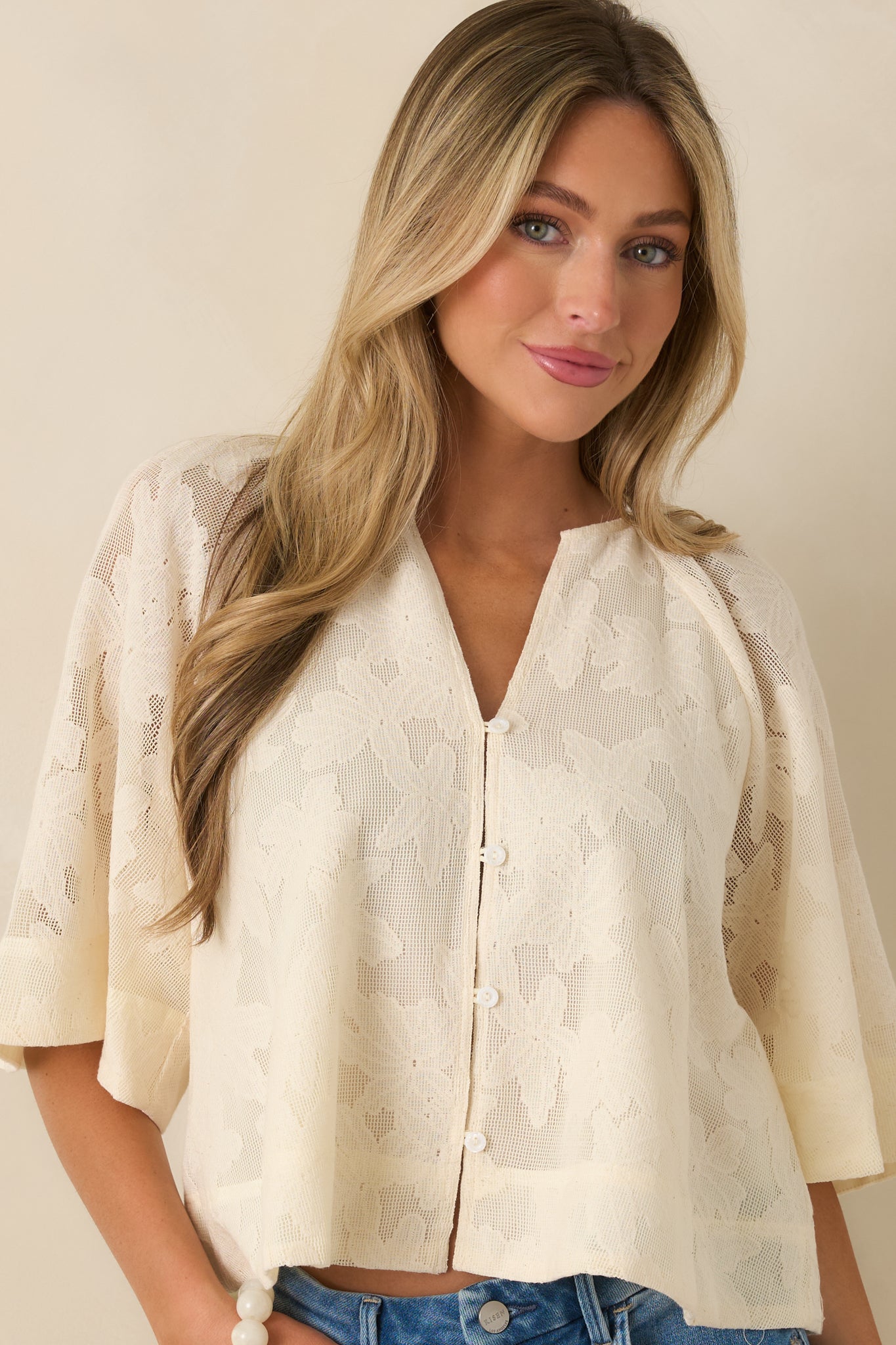 Ivory blouse highlighting tonal embroidered patterns and front button closure.