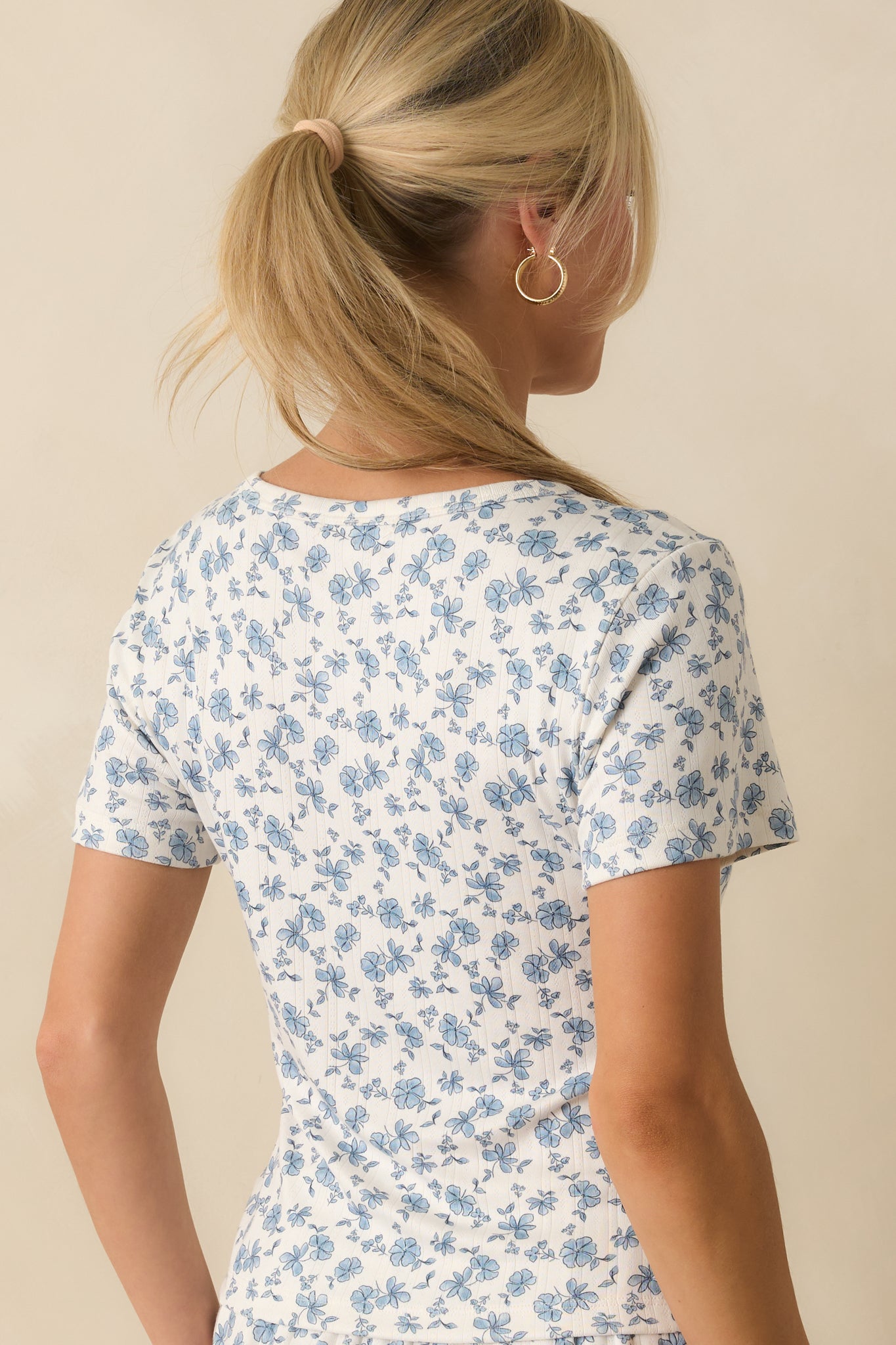 Rear view of the ivory and blue floral top with ribbed knit finish and fitted cut.