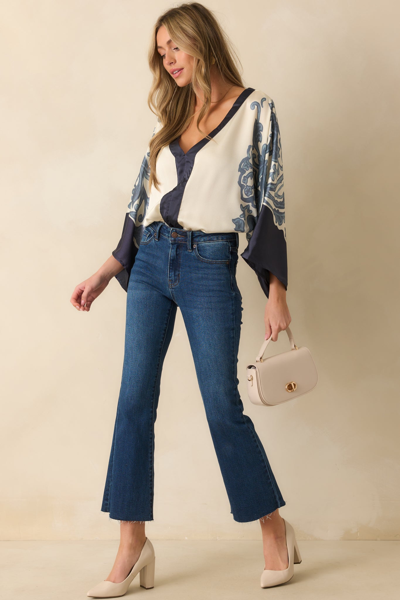 Ivory bodysuit with ornate navy border print and kimono-style long sleeves, highlighting the deep v-neck.