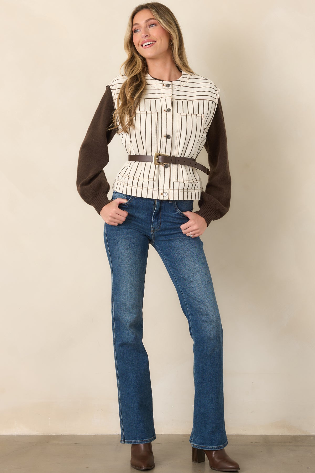 Relaxed ivory vest featuring vertical brown pinstripes, horizontal yoke striping, cap-style shoulders, and a utilitarian button-front finish.