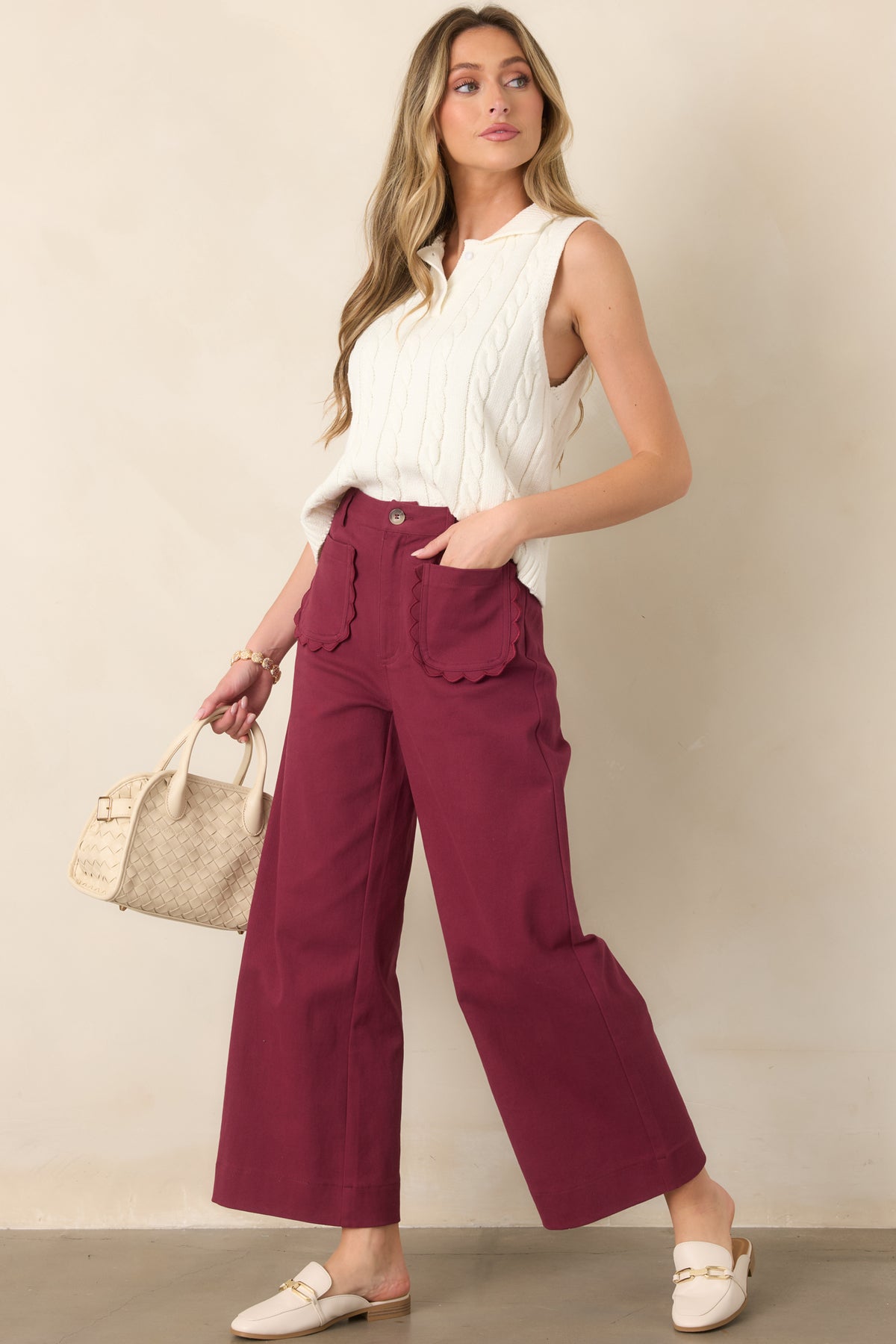 Ivory cable-knit vest with a polished collared neckline, button placket, wide ribbed hem, and easy relaxed silhouette.