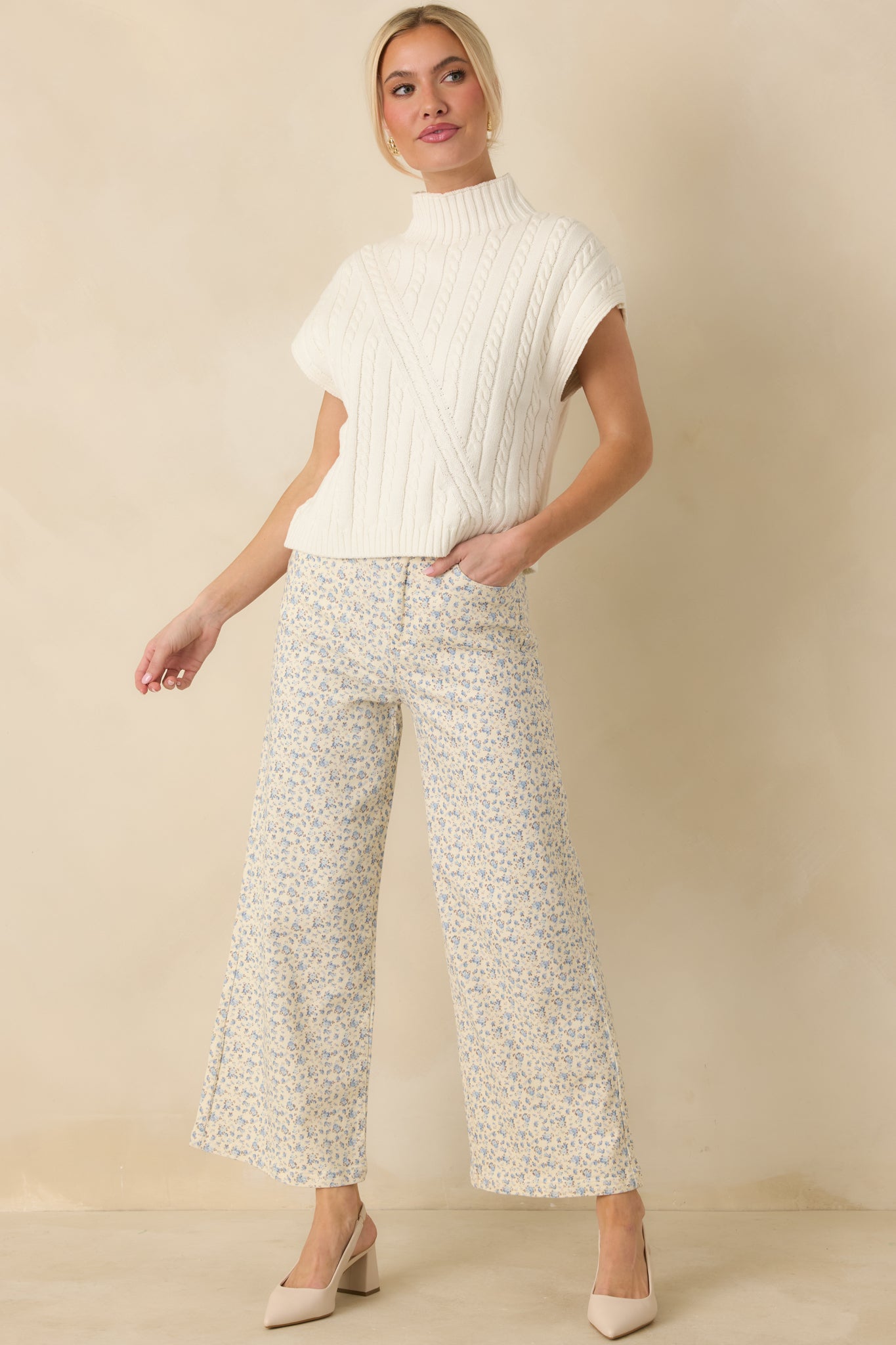 Ivory cable knit mock neck top shown from the front, highlighting the sleeveless design and polished ribbed finishes.