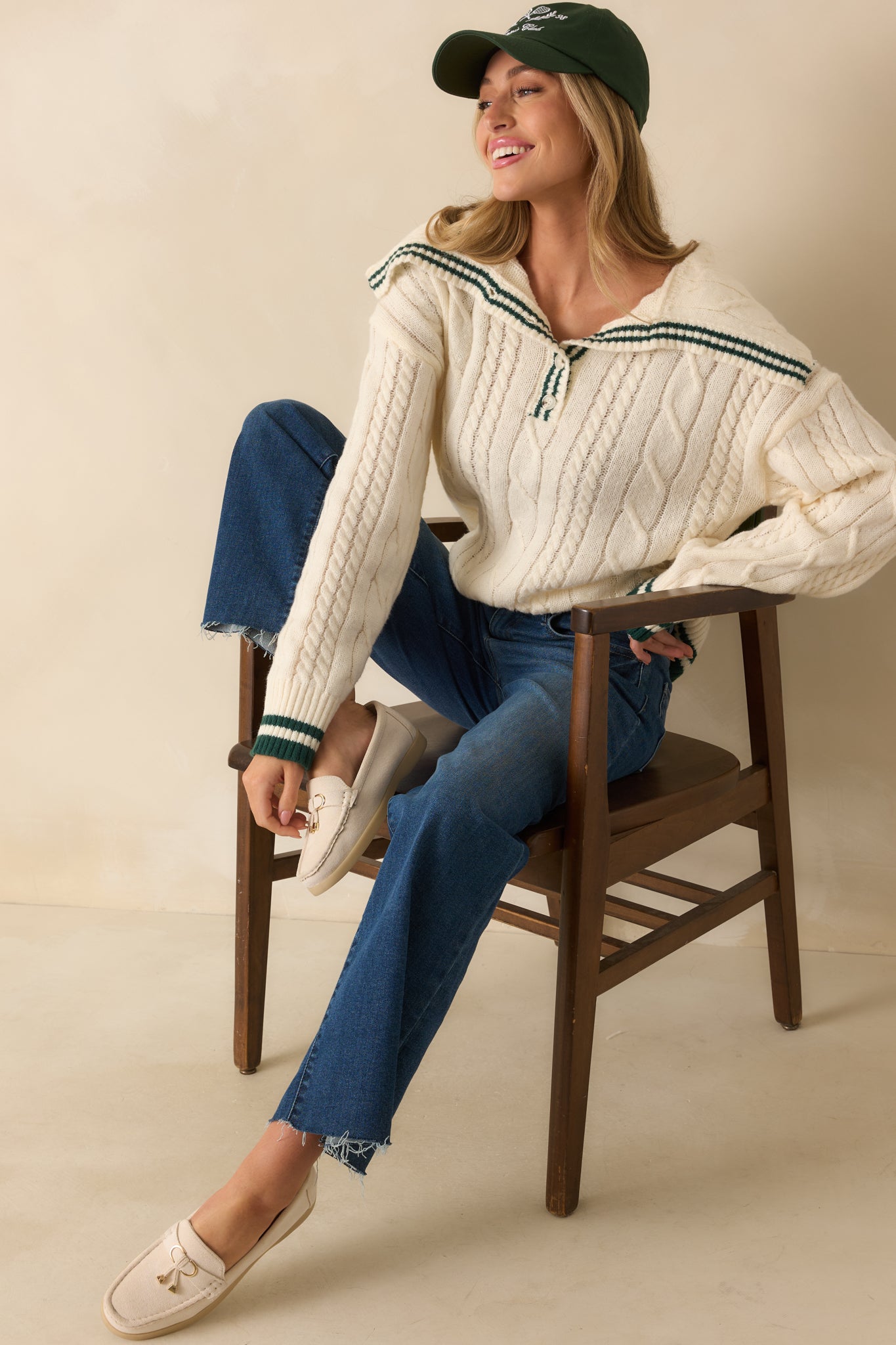 Relaxed fit cable knit sweater in ivory with long sleeves, ribbed cuffs, and contrasting hunter green stripes.