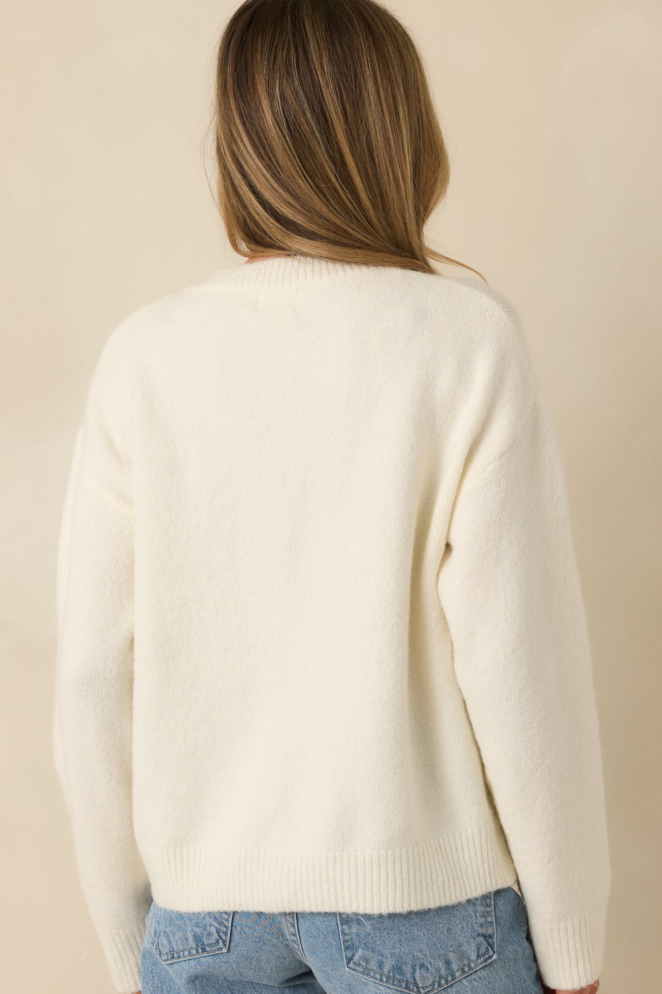 Back view of the ivory cardigan showing a smooth solid knit finish, long sleeves, and ribbed trim at the hem and cuffs.