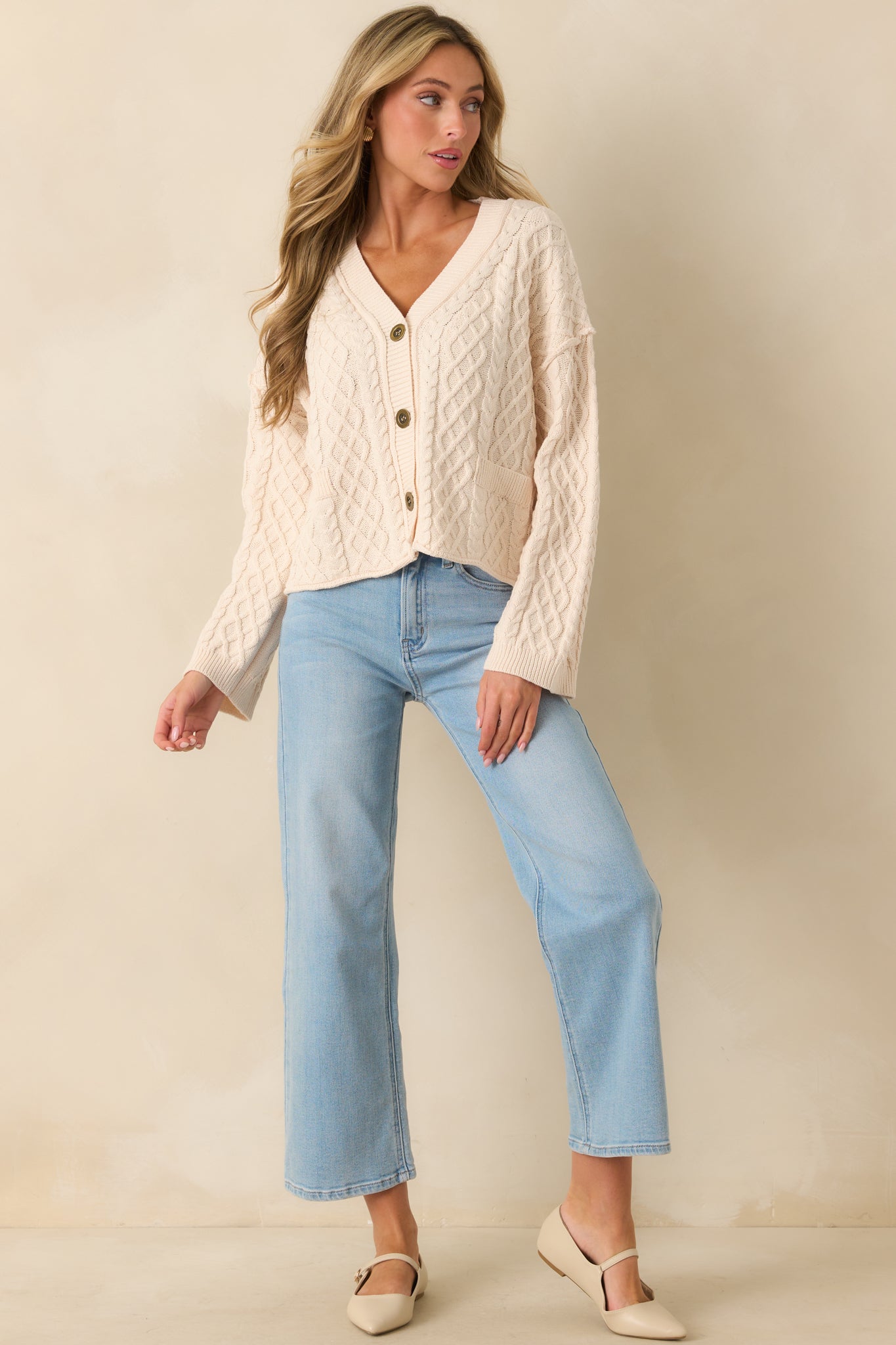 Ivory cardigan with a v-neckline, cable knit design, and relaxed fit.