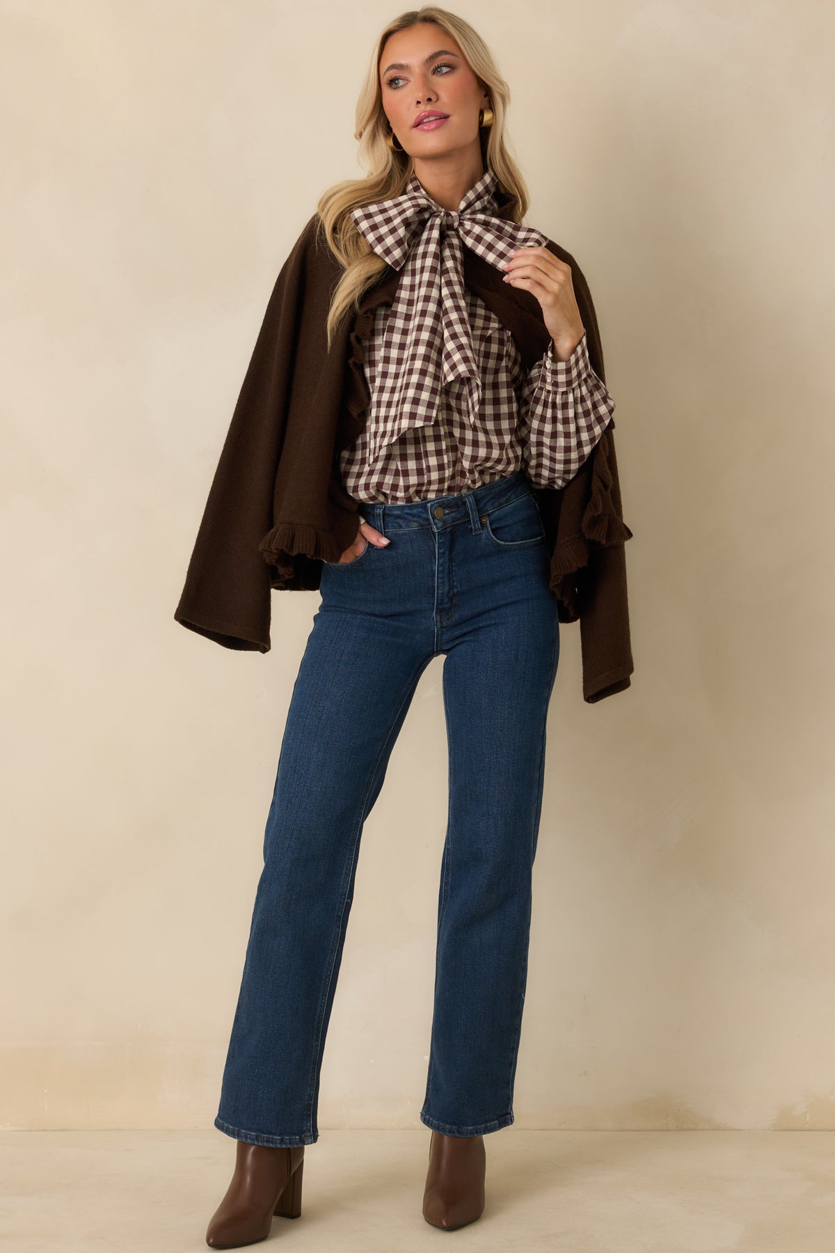 Ivory and chocolate gingham blouse featuring a dramatic tie neckline, long gathered sleeves, and hidden front buttons.
