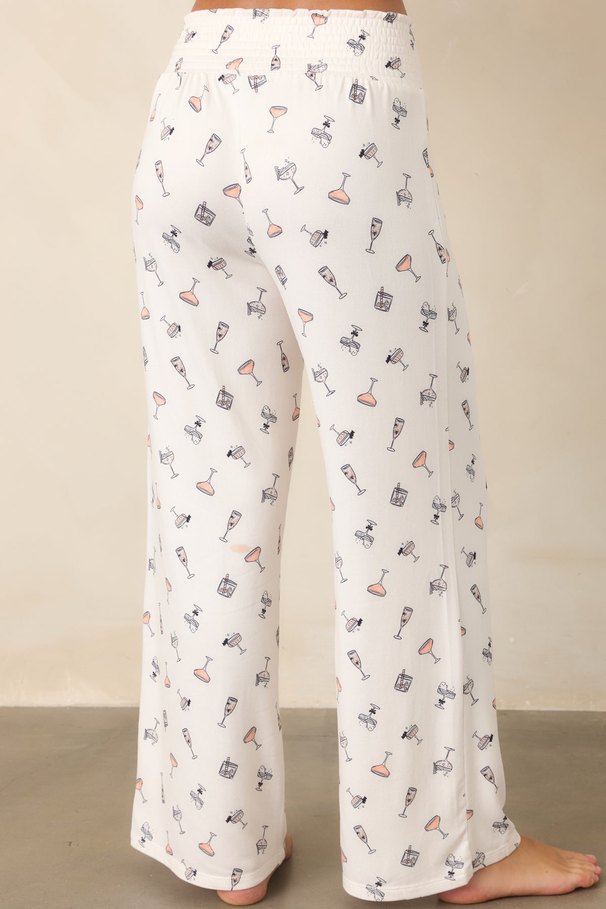 Rear view of the ivory cocktail-print pants showing the wide smocked waistband and relaxed wide-leg silhouette.