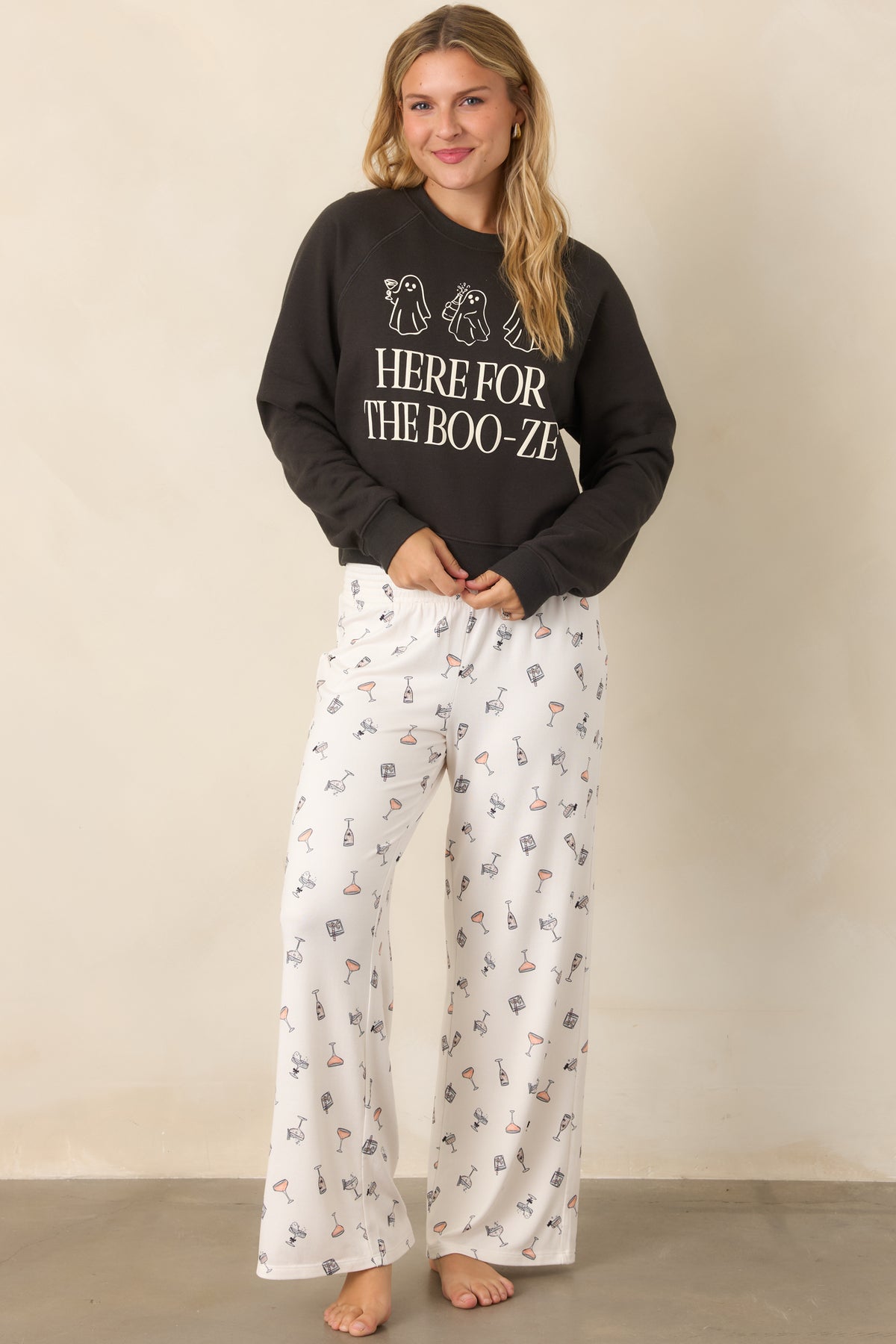 Flowy ivory pants showcasing an allover cocktail print, subtle spooky accents, and a comfortable smocked waistband above the wide-leg silhouette.