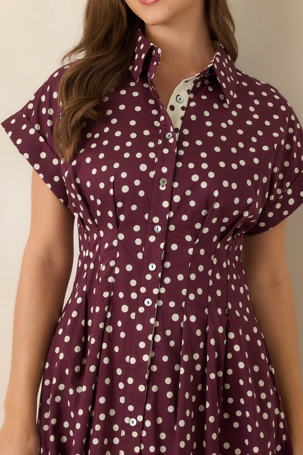 Plum polka dot cotton midi dress featuring a classic collar, full button-front closure, short sleeves, defined waist seams, and a softly flared skirt.