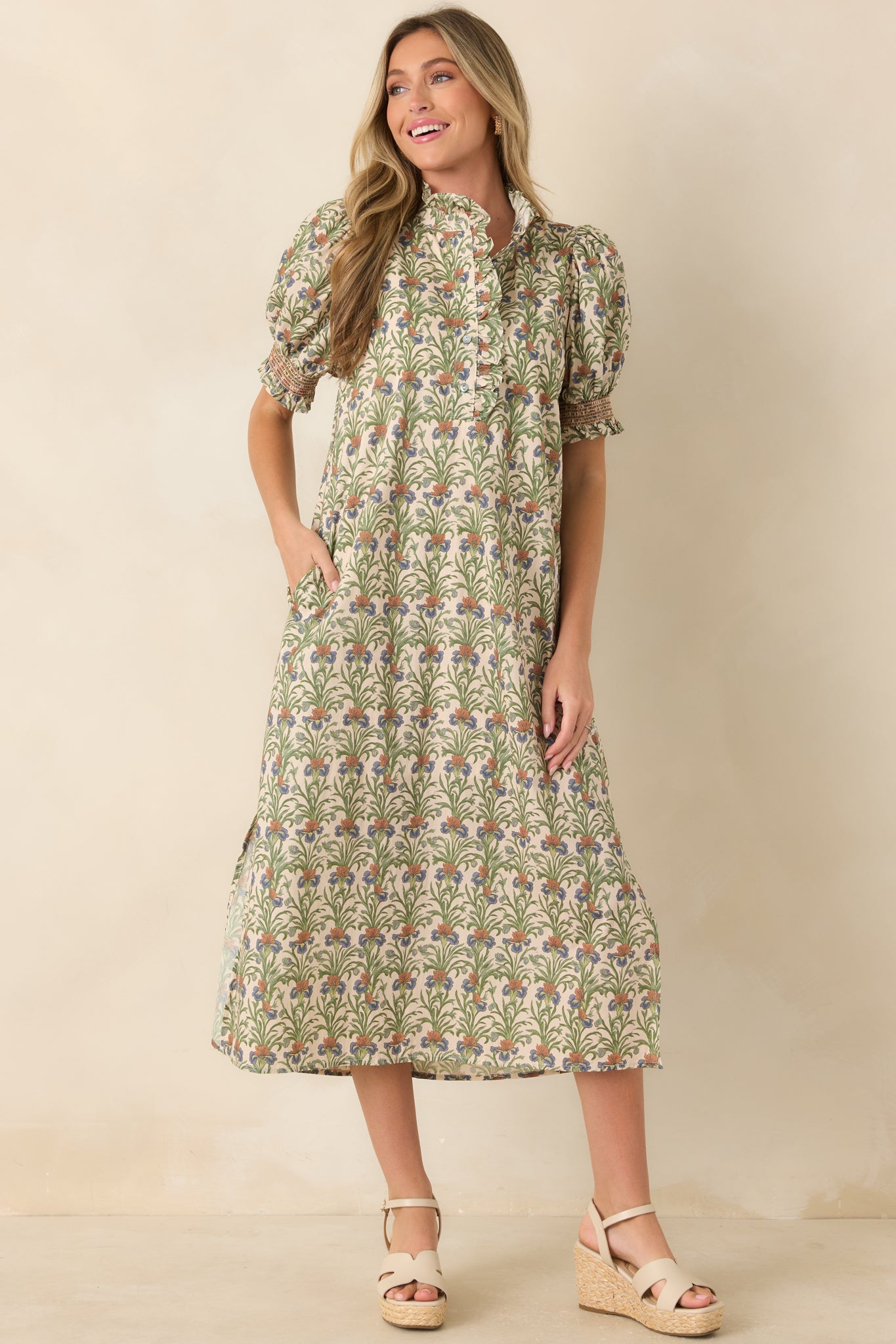 Ivory cotton midi dress featuring a mossy green botanical print, ruffled neckline, puff sleeves, and a relaxed silhouette with seasonal charm.