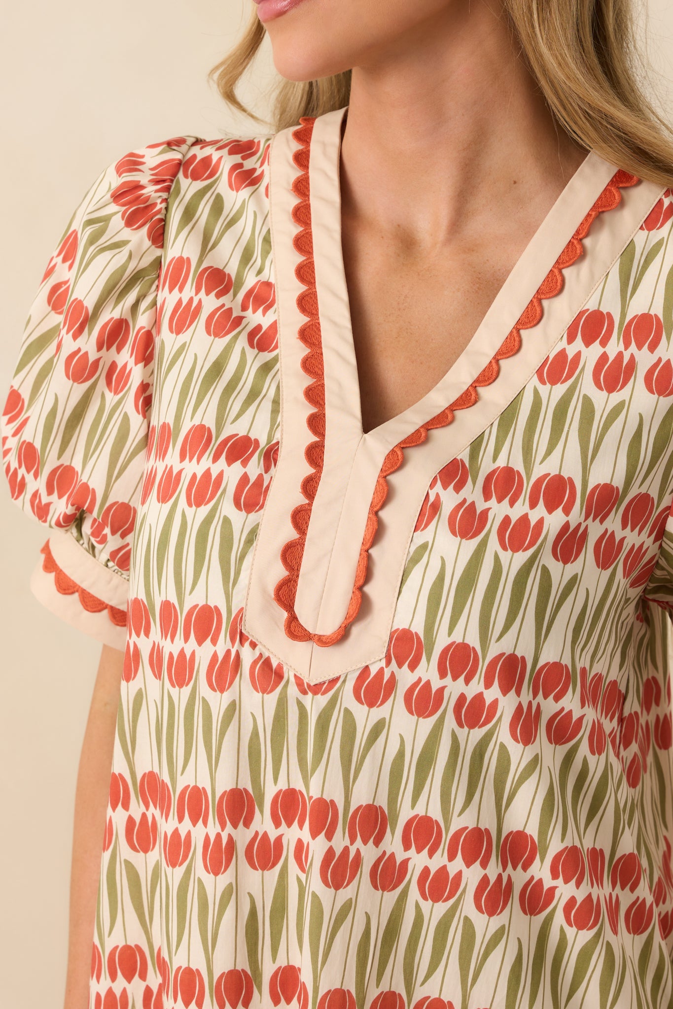 Scalloped embroidered trim around the neckline of the ivory cotton mini dress with tulip print.