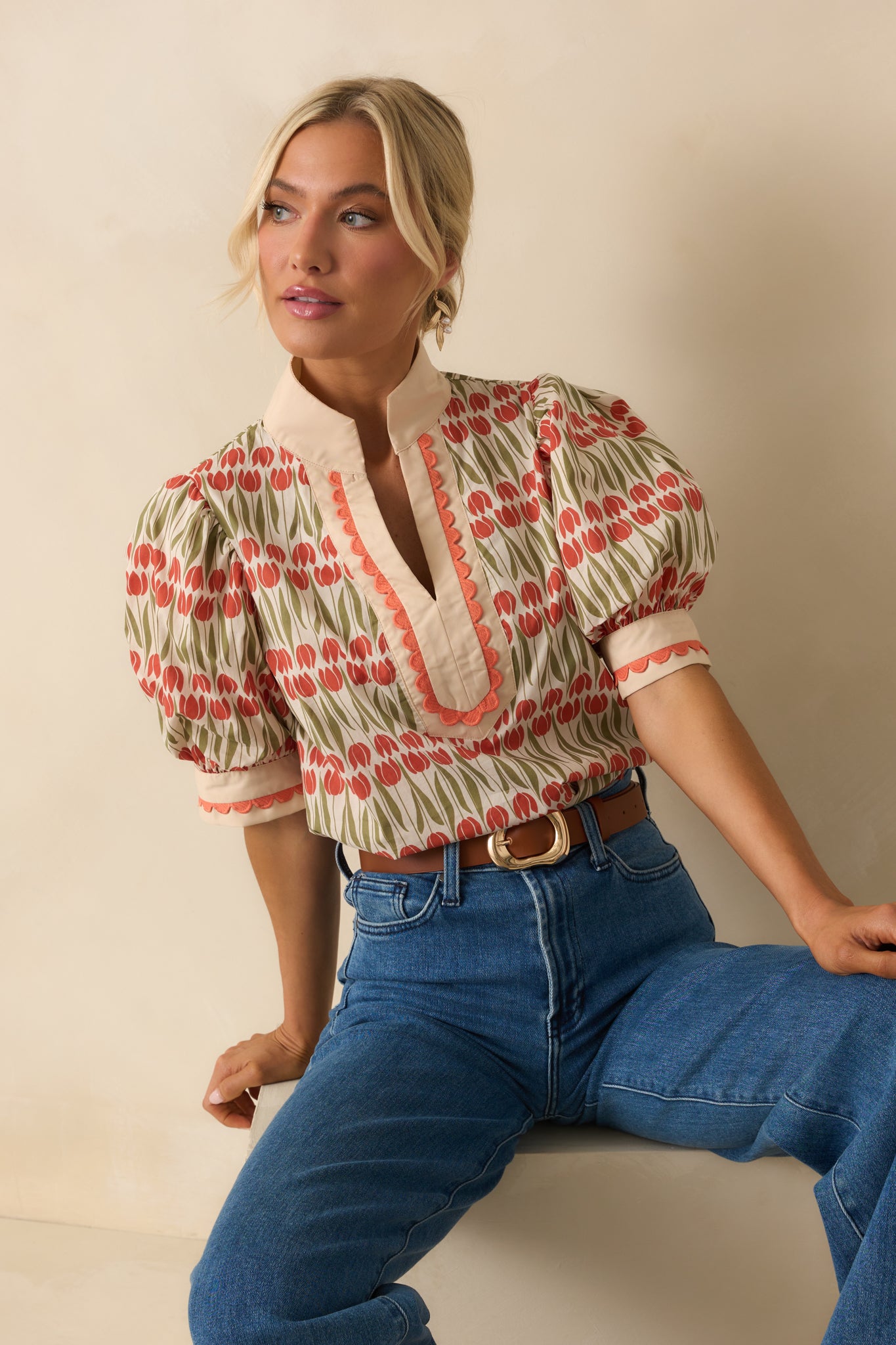 Ivory cotton top patterned with rust orange tulip florals and green stems, finished with puff sleeves and scalloped embroidered trim.