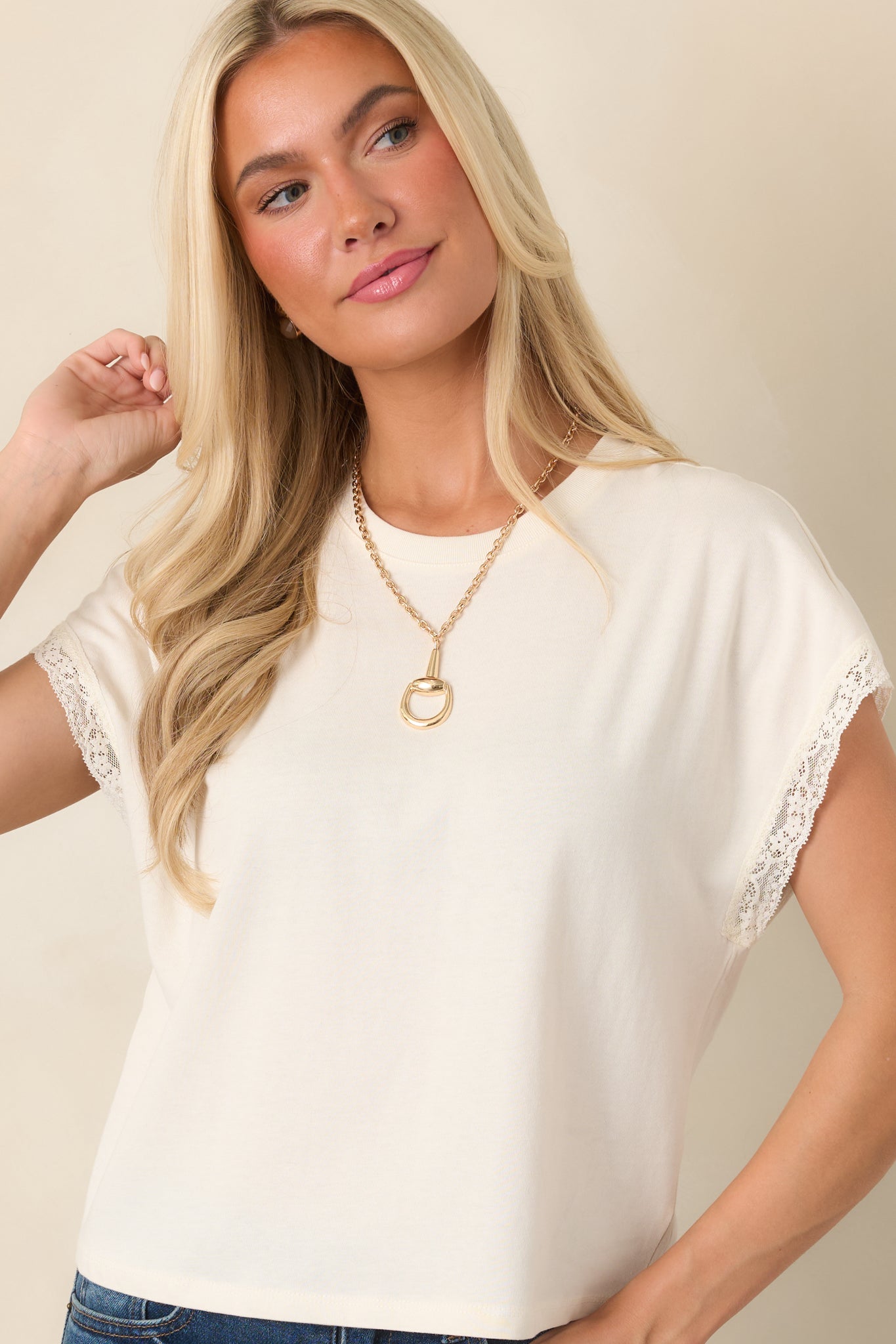 Close view of the ivory top highlighting the classic crew neckline and softly structured cap-style muscle sleeves.