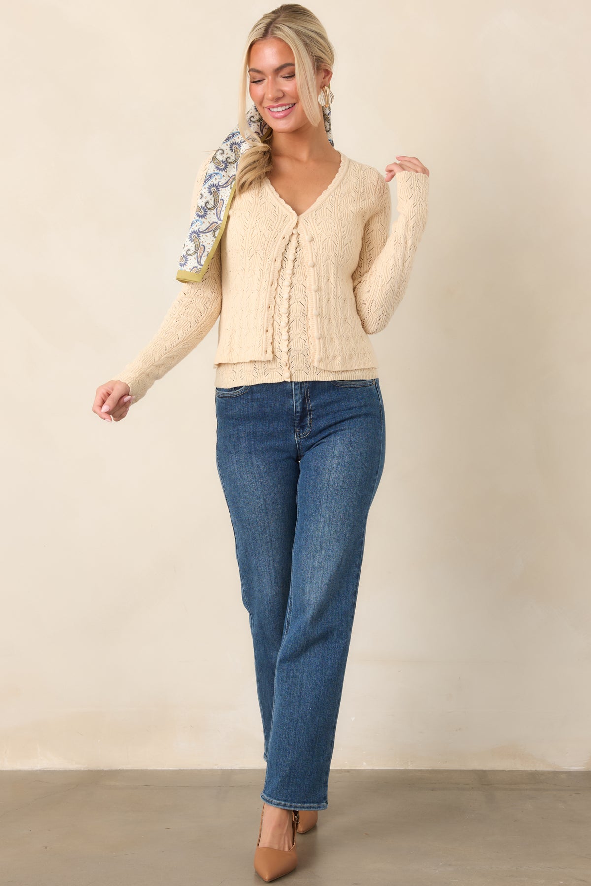 Ivory cropped cardigan with an intricate pointelle knit pattern, scalloped V-neckline, long sleeves, and a neat button-front finish.