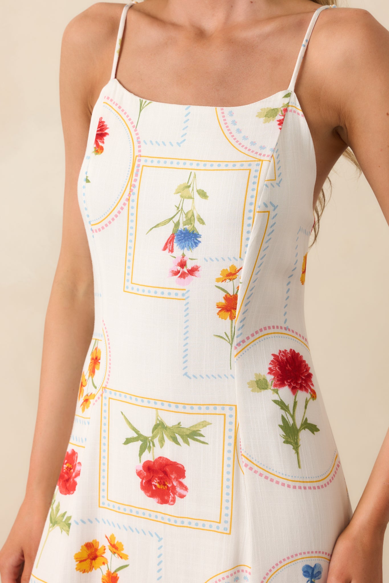 A detailed close-up capturing the soft texture and stitched patchwork pattern of the ivory dress's fabric.