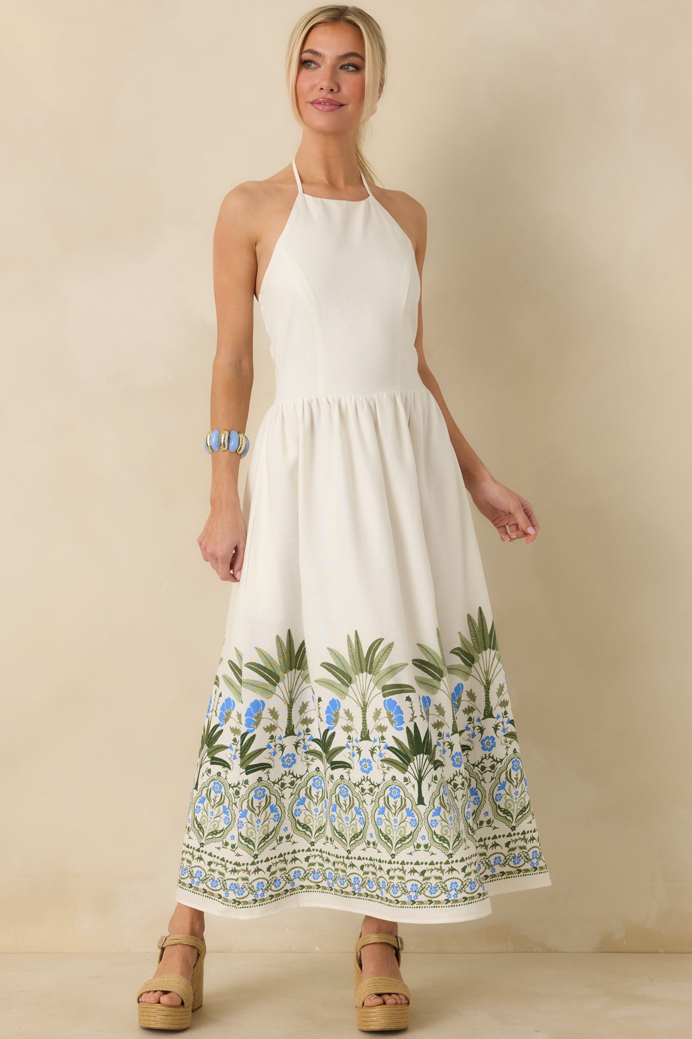 Ivory dress with green and blue floral and palm border print along hem.