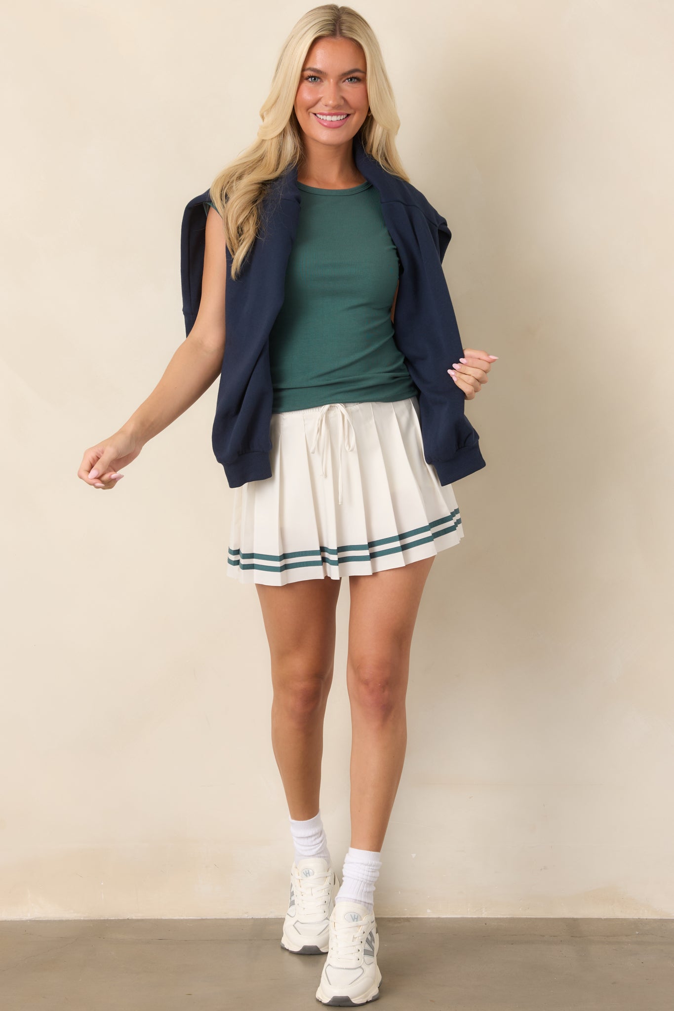 Ivory skort featuring an elastic high-rise waist, Emerald Cove accent stripes, adjustable drawcord, and integrated biker shorts for added coverage.