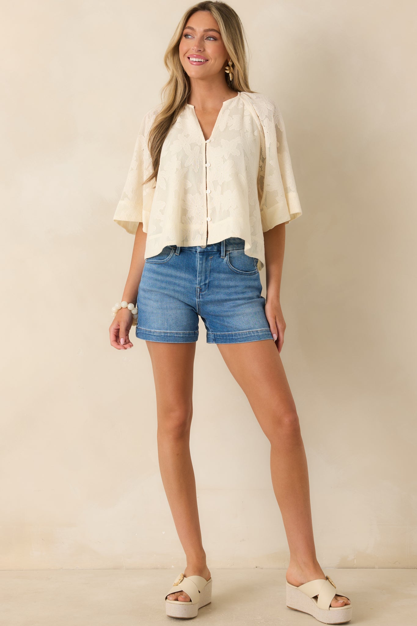 Ivory eyelet embroidered blouse with V-neckline and button-front closure.