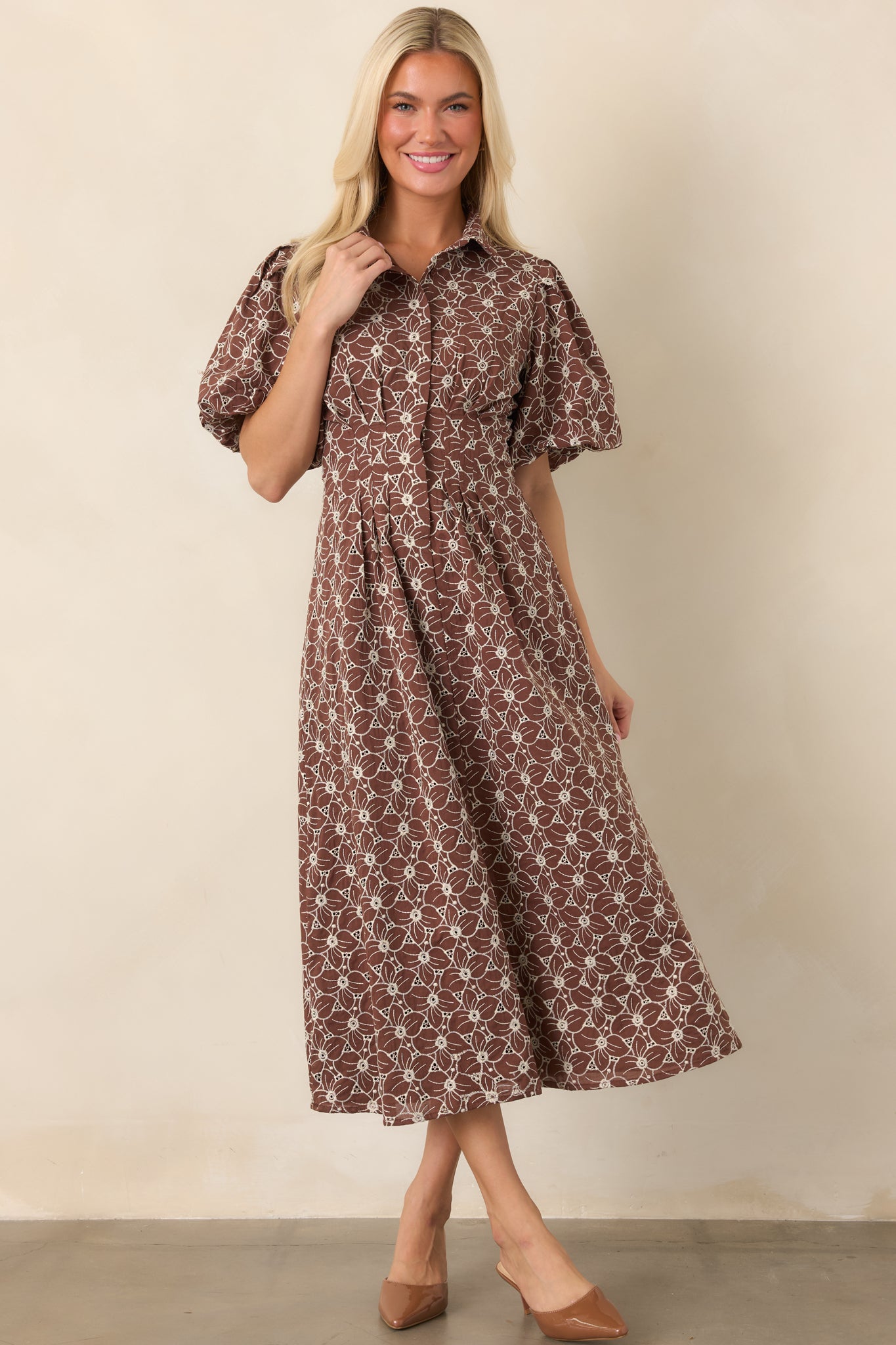 Ivory eyelet midi dress with an embroidered floral pattern, button-front bodice, defined waist, puff sleeves, and a generously gathered skirt.